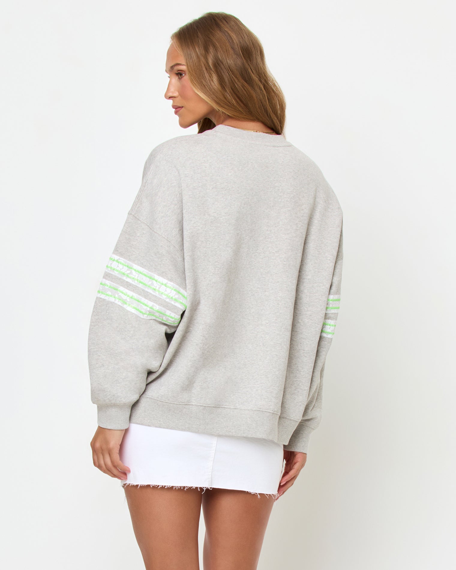 Legend Sweatshirt - Limeade Back studio view of the Legend Sweatshirt in Limeade, a heather gray oversized crewneck sweatshirt, styled with a white denim skirt.