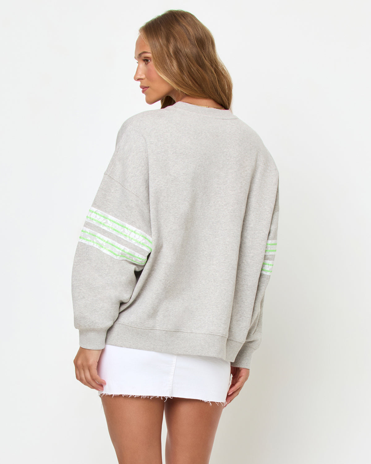 Legend Sweatshirt - Limeade Back studio view of the Legend Sweatshirt in Limeade, a heather gray oversized crewneck sweatshirt, styled with a white denim skirt.