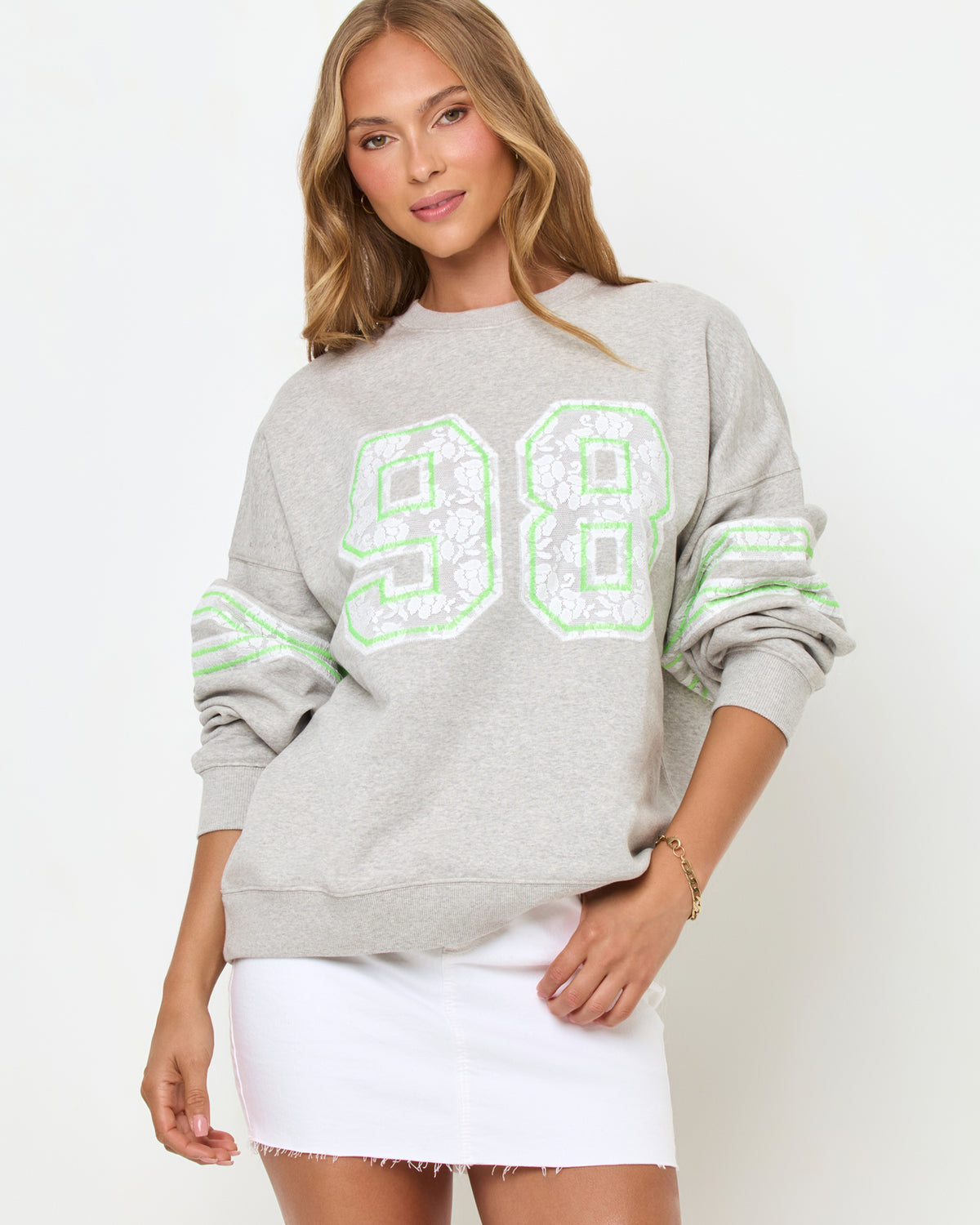 Legend Sweatshirt - Limeade Front studio view of the Legend Sweatshirt in Limeade, a heather gray oversized crewneck sweatshirt with a neon green "98" graphic on the chest, styled with a white denim skirt.