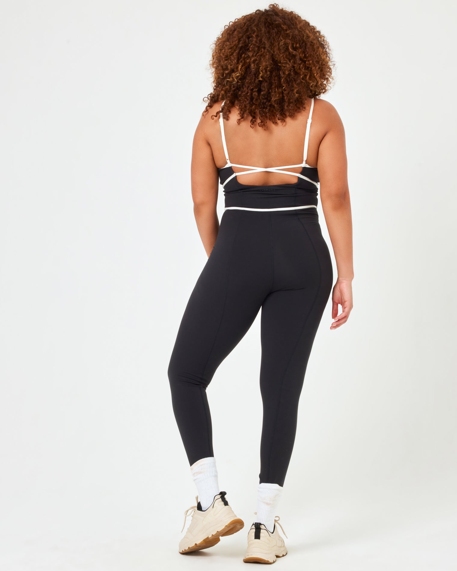 Ace Jumpsuit - Black-Cream Back view of model wearing the Ace Jumpsuit in black-cream in XL showing the open back with cream piping detail.