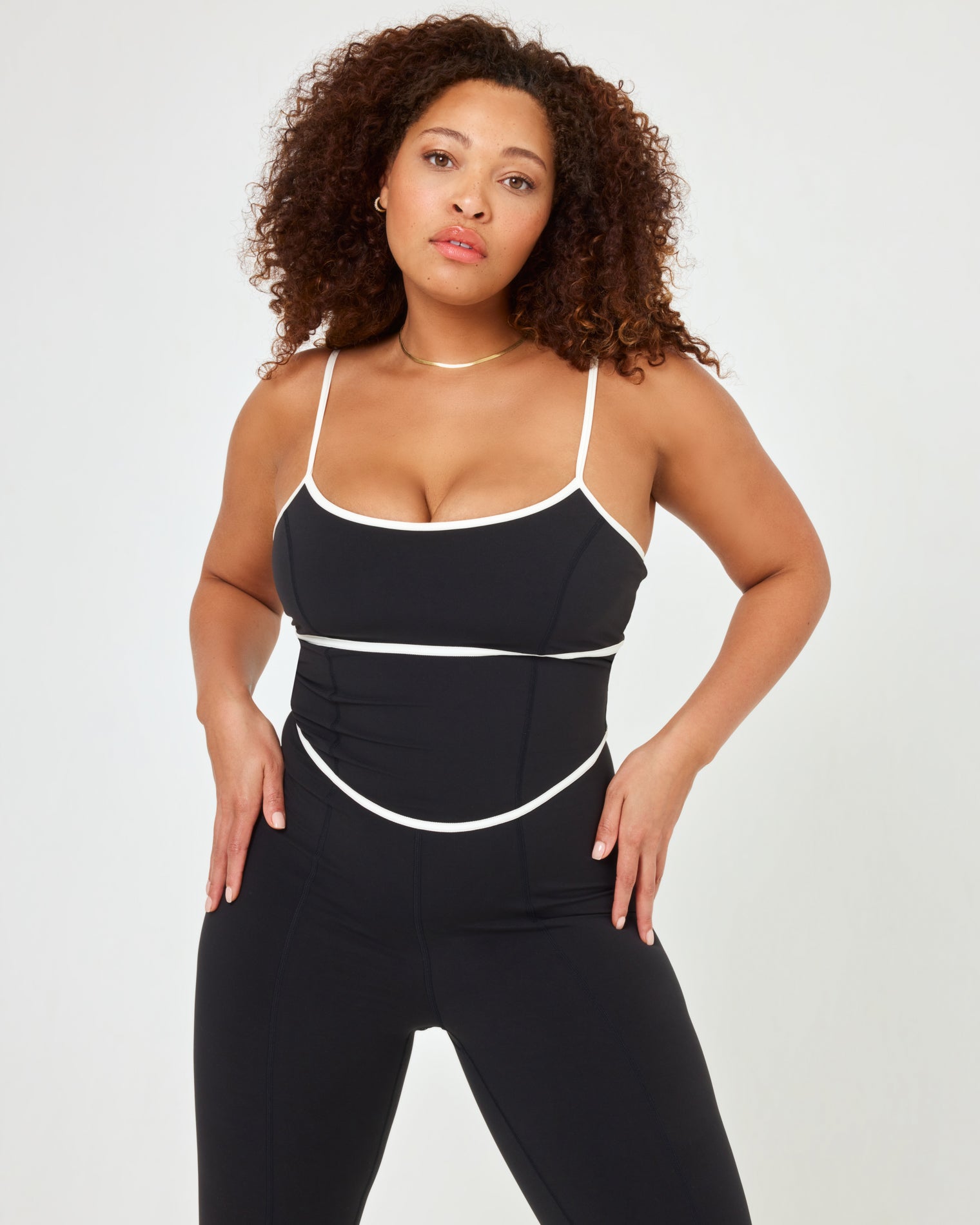 Ace Jumpsuit - Black-Cream Close-up view of model wearing the Ace Jumpsuit in black-cream in XL showing the cream contrast piping and cutout detail.