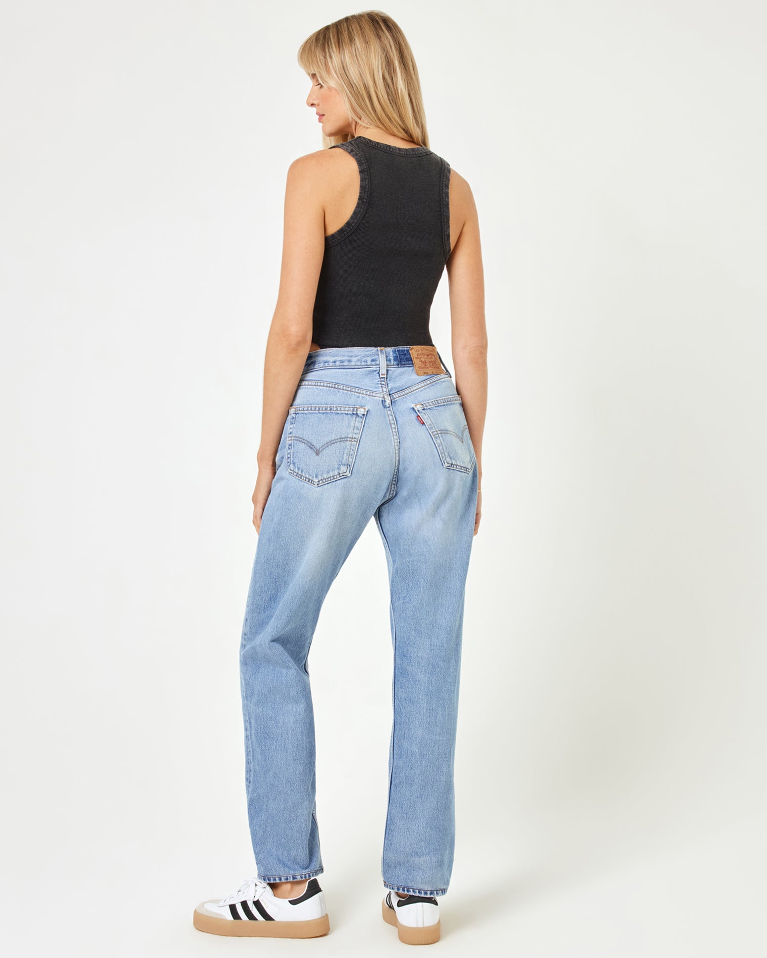 aligrace Brigette Baggy Denim Pant Angled back view of a model wearing the LSPACE aligrace Brigette Baggy Denim Pant in blue, styled with a black ribbed crop tank and sneakers.