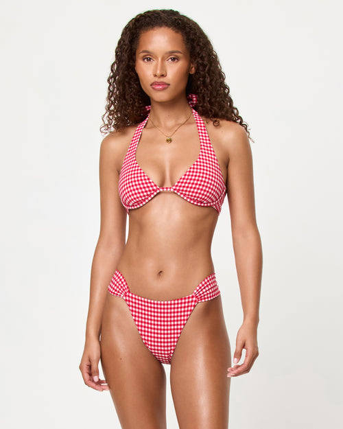 Front view of a model wearing the LSPACE lipstick red Isa Bikini Top and Dolce Bikini Bottom with a triangle halter neckline and knotted center front detail in gingham print.