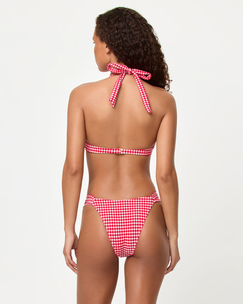Back view of a model wearing the LSPACE lipstick red Isa Bikini Top and Dolce Bikini bottom showing the halter neck tie and band back closure in gingham print.