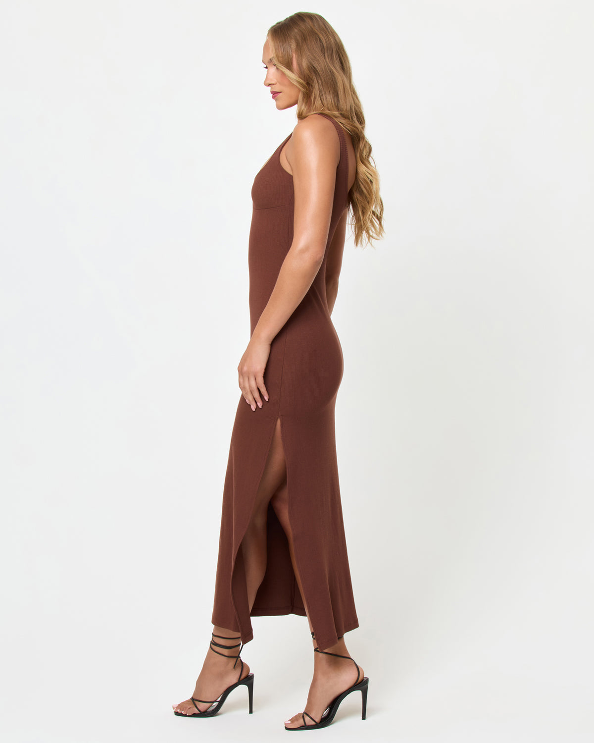 Alexis Dress - Cafe Side view of a model wearing the LSPACE Alexis Dress in cafe, showing the fitted silhouette and side slit of the chocolate brown ribbed midi dress.