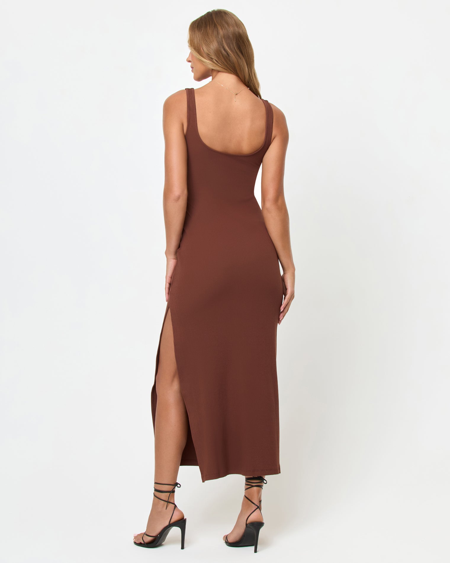 Alexis Dress - Cafe Back view of a model wearing the LSPACE Alexis Dress in cafe, showing the thick straps, open back, and side slit of the fitted ribbed midi dress in chocolate brown.