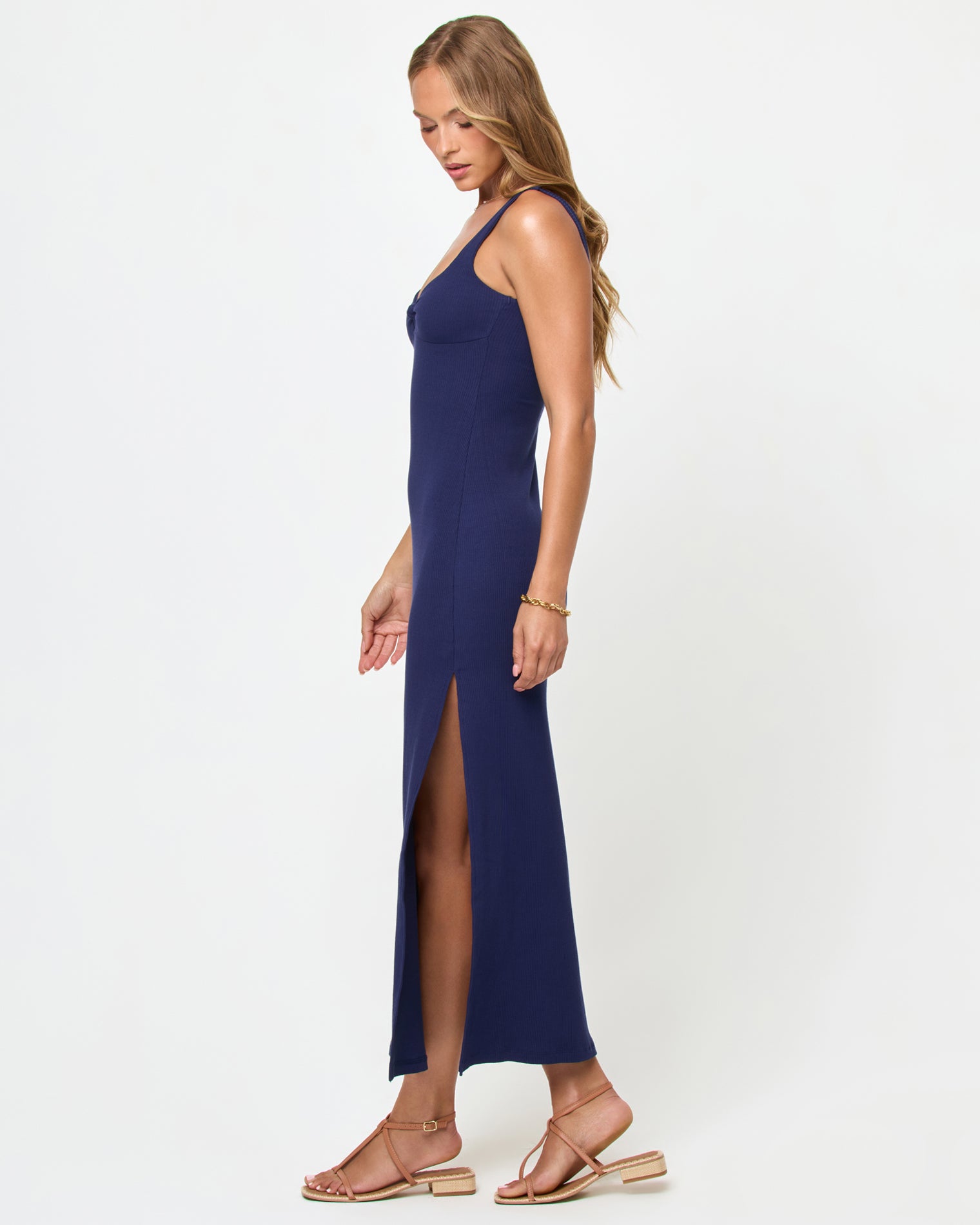 Alexis Dress - Midnight Blue Side view of a model wearing the LSPACE Alexis Dress in midnight blue, showing the fitted silhouette and side slit of the navy ribbed midi dress.