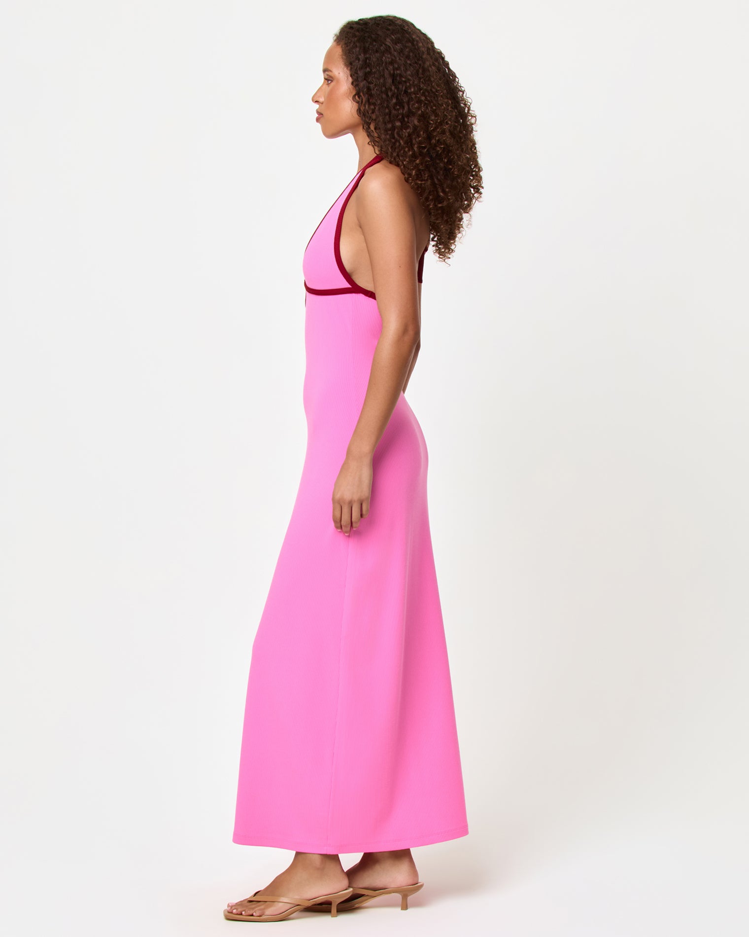 Shea Maxi Dress - Pink-Simmer Side view of a model wearing the LSPACE Shea Maxi Dress in pink-simmer, showing the fitted silhouette and full length of the dress with simmer contrast trim detail.
