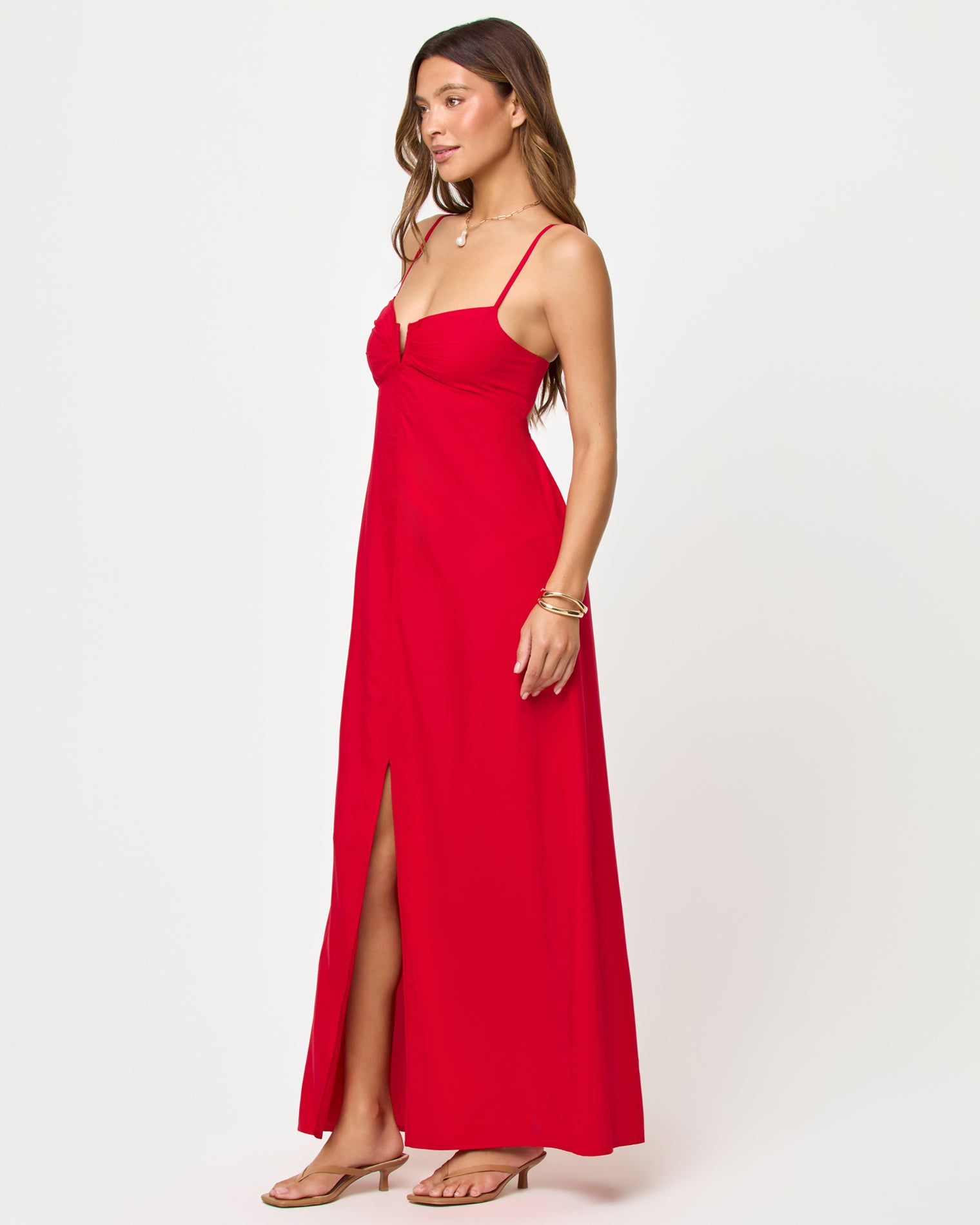 Chara Maxi Dress - Lipstick Red Side view of model wearing the LSPACE Chara Maxi Dress in lipstick red, showing the floor-length silhouette and front slit.