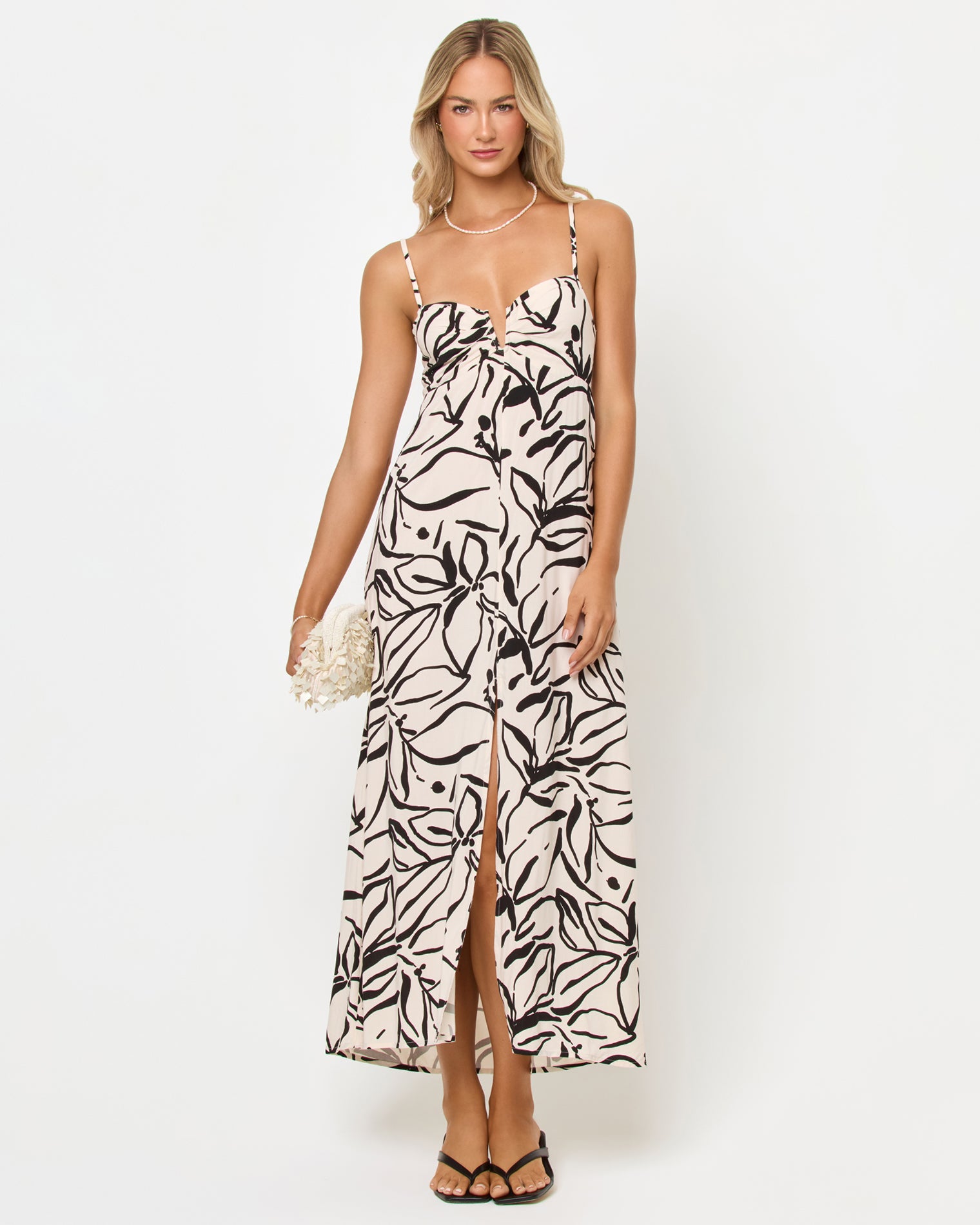 Chara Maxi Dress - Heavy Petal Front view of a model wearing the LSPACE Chara Maxi Dress in heavy petal, a black and white abstract floral print maxi dress with spaghetti straps and a front slit, on a white studio background.