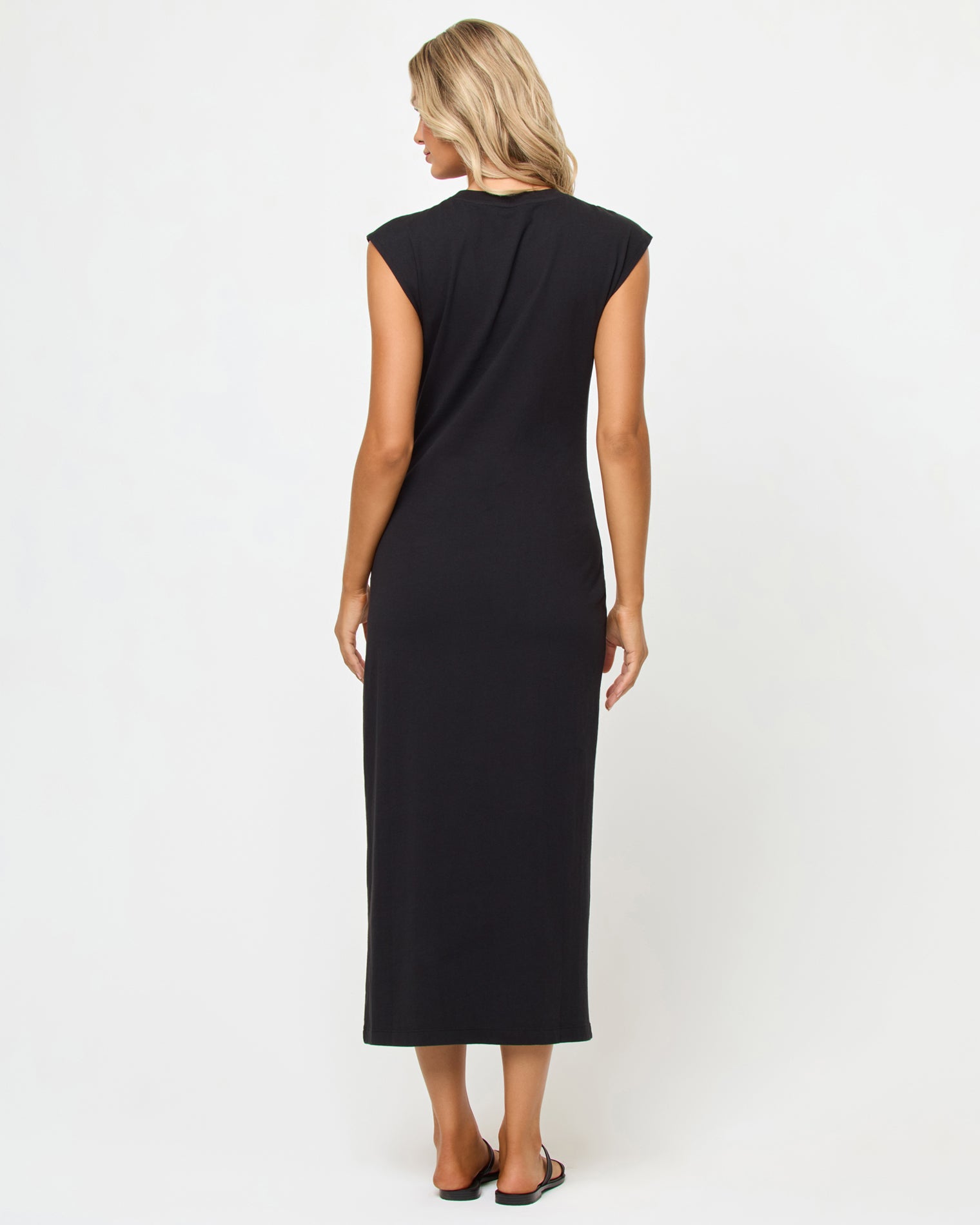 Sacha Maxi Dress - Black Back view of a model wearing the LSPACE Sacha Maxi Dress in black, a black sleeveless maxi dress with cap sleeves and a clean, streamlined back, showing the full maxi length.
