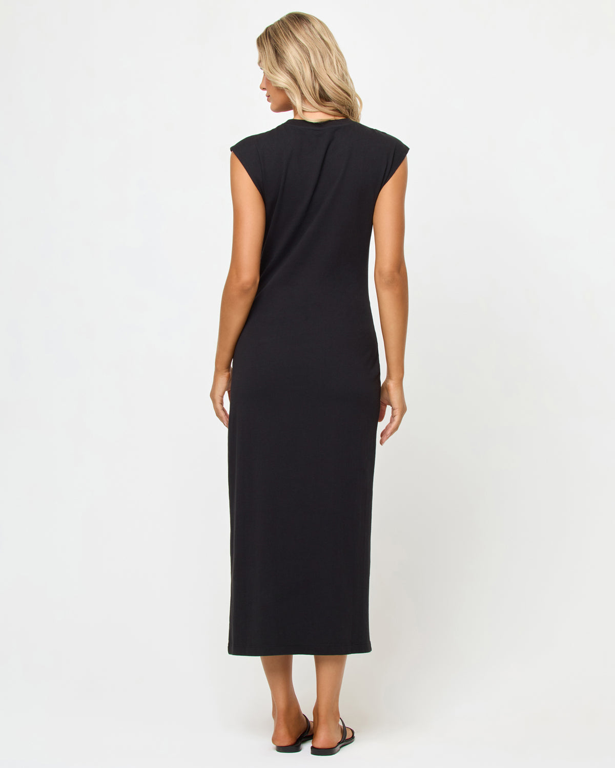 Sacha Maxi Dress - Black Back view of a model wearing the LSPACE Sacha Maxi Dress in black, a black sleeveless maxi dress with cap sleeves and a clean, streamlined back, showing the full maxi length.