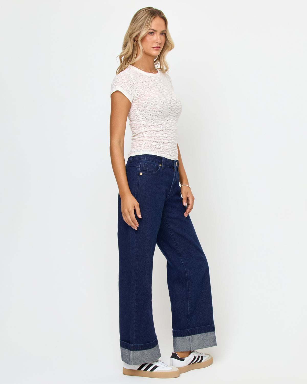 Lily Rose Top - Cream Side view of a model wearing the LSPACE Lily Rose Top in cream, showing the cropped length and lace-textured short sleeves, styled with wide-leg dark jeans.