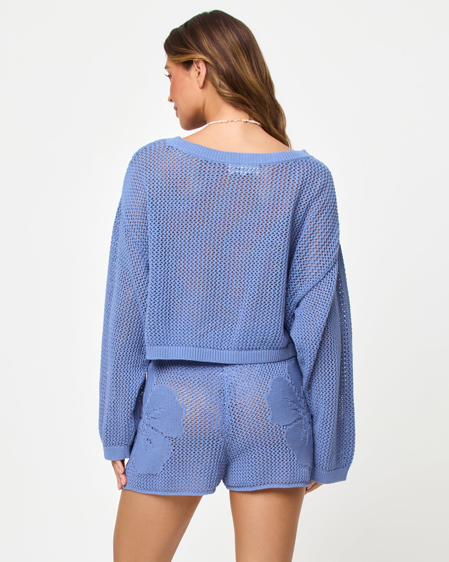 Island Time Sweater - Chambray Back view of a model wearing the LSPACE Island Time Sweater in Chambray, styled with the matching Island Time Short, showing the open-knit crochet construction and relaxed fit.
