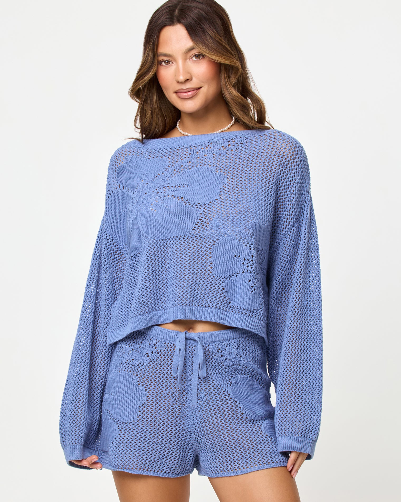 Island Time Sweater - Chambray Close-up of a model wearing the LSPACE Island Time Sweater in Chambray, styled with the matching Island Time Short, highlighting the open-knit crochet floral design and long sleeves.