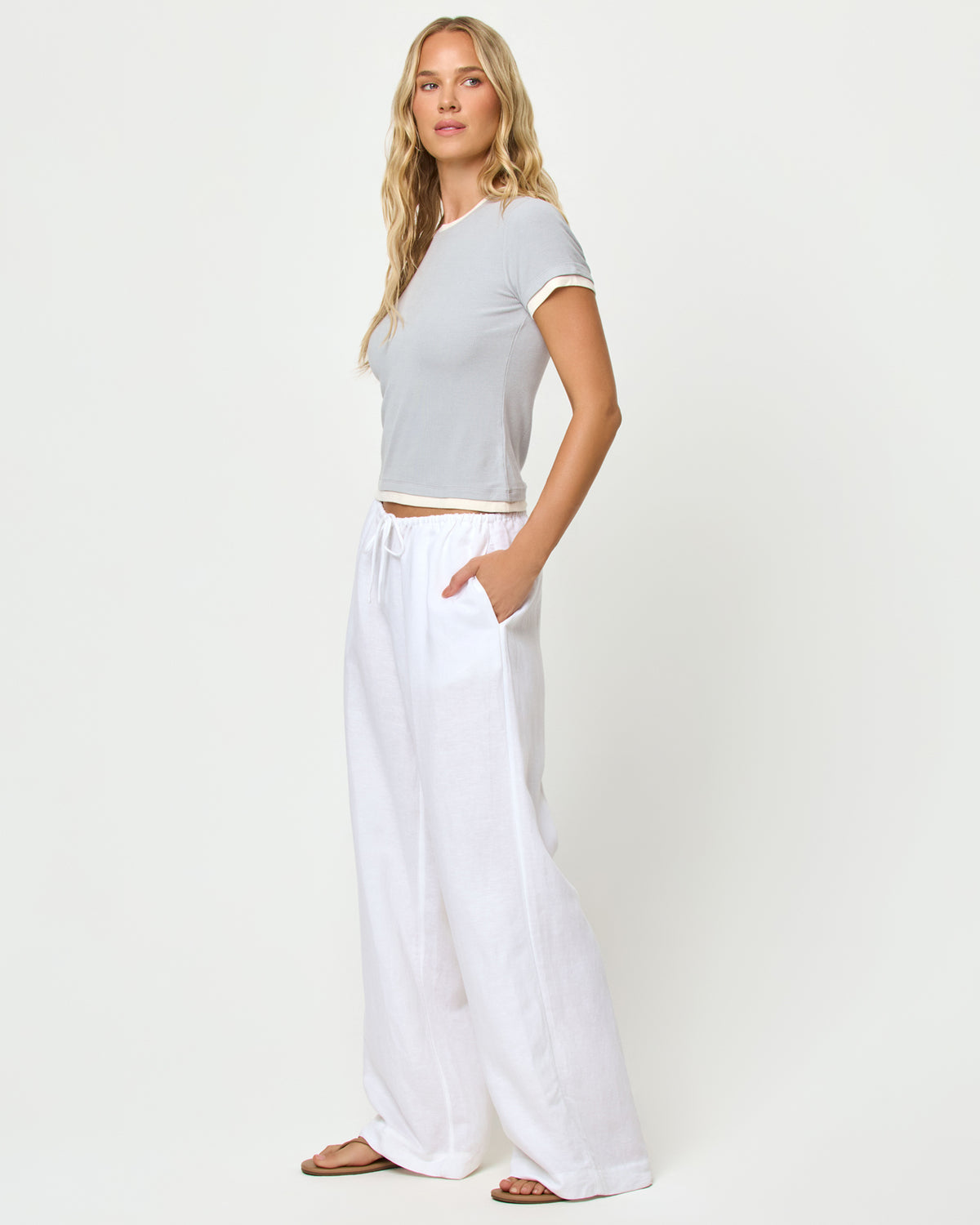 Range Top - Gray-Cream Side view of model wearing the Range top in gray-cream, styled with the Nina Pant in white.