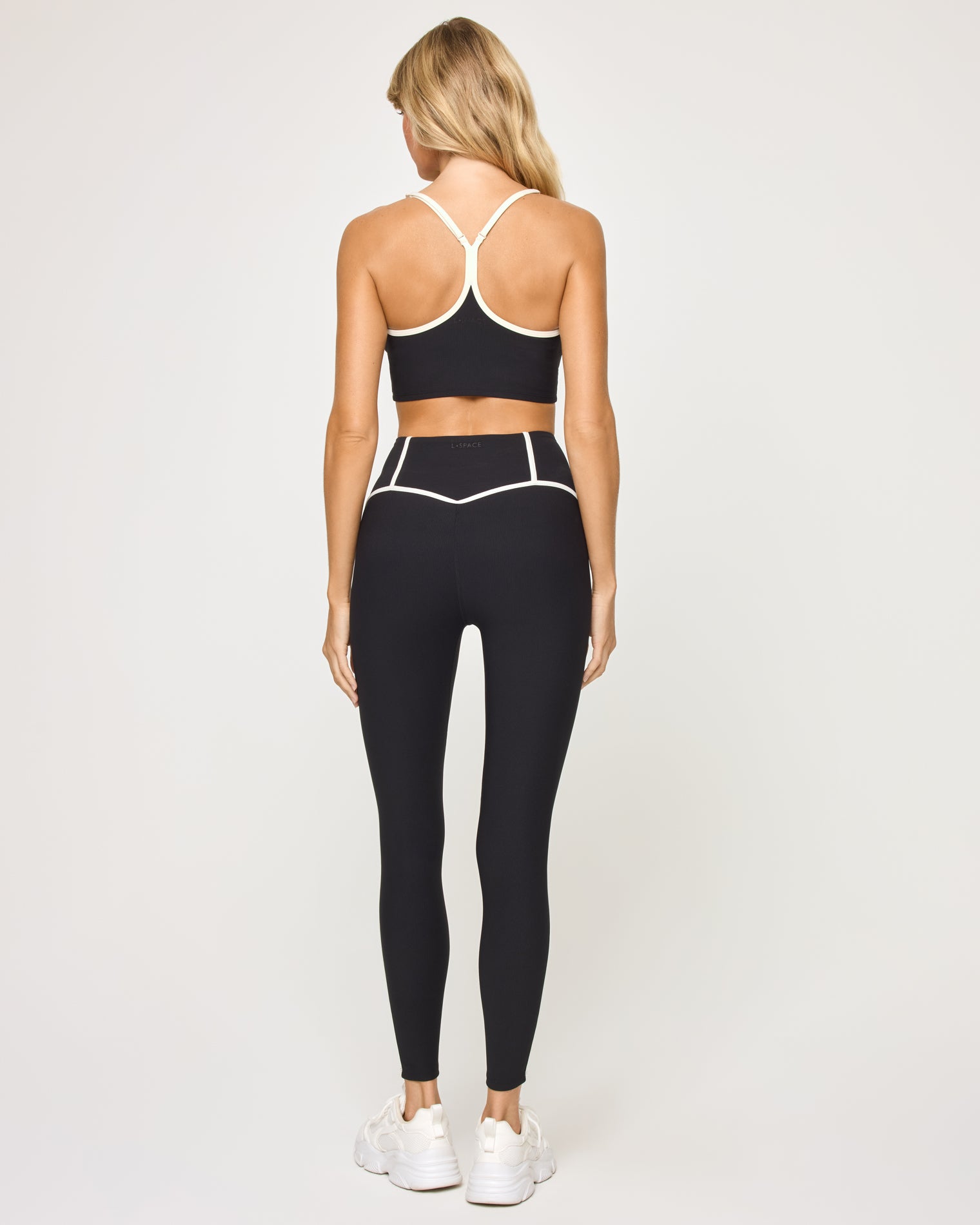 Revel Legging - Black-Cream Back view of model wearing the Revel Legging in black-cream showing the cream piping on the waistband, with matching bra showing crossback detail.