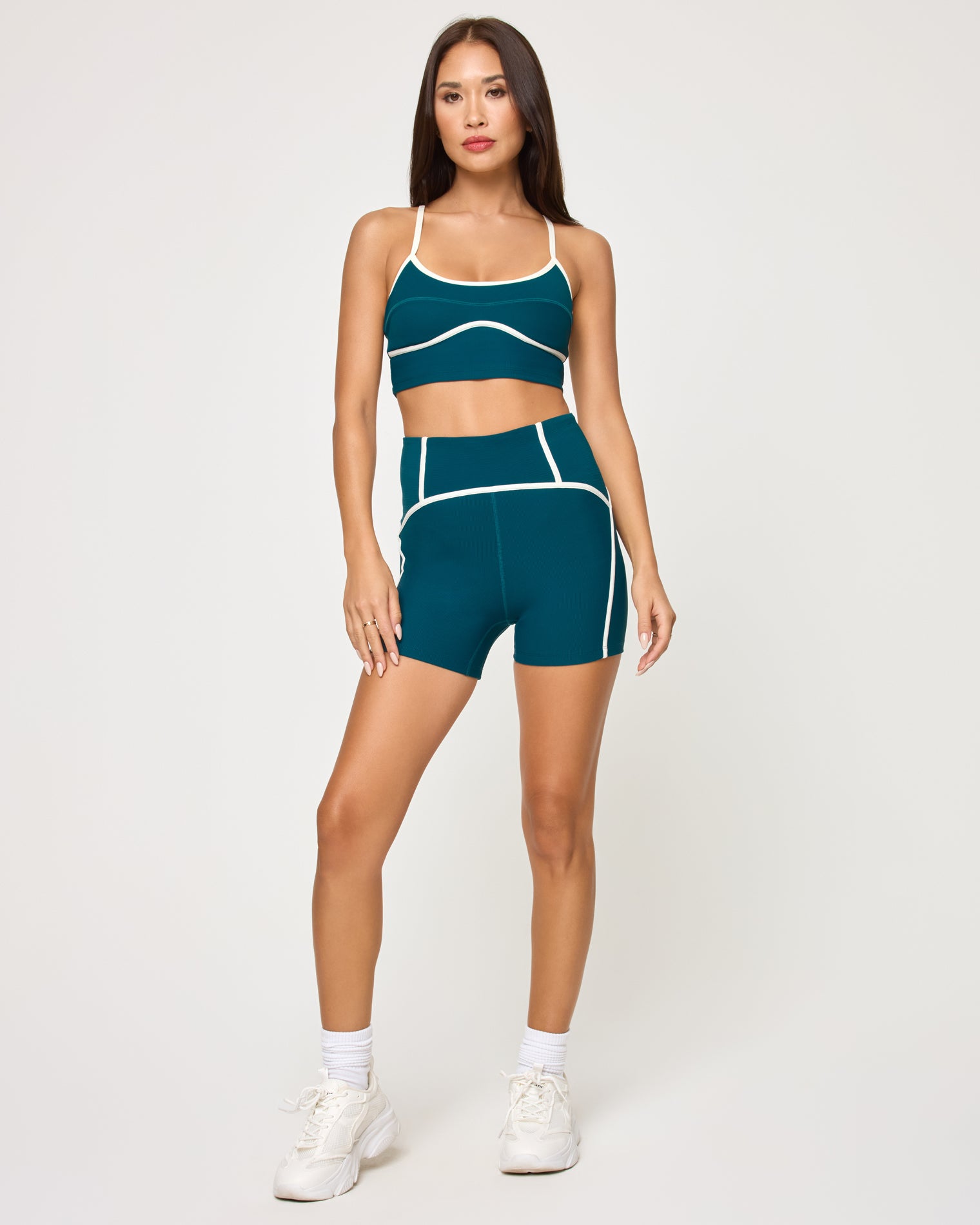 Revel Top - Deep Teal-Cream Front view of model wearing the Revel Top in deep teal-cream with matching deep teal-cream Revel Short, white socks and white sneakers.