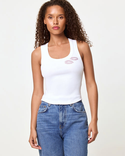 Front view of a model wearing the LSPACE Ash Tank in muah, a white cropped ribbed racerback tank with a rhinestone lips graphic on the chest, styled with medium wash blue jeans.