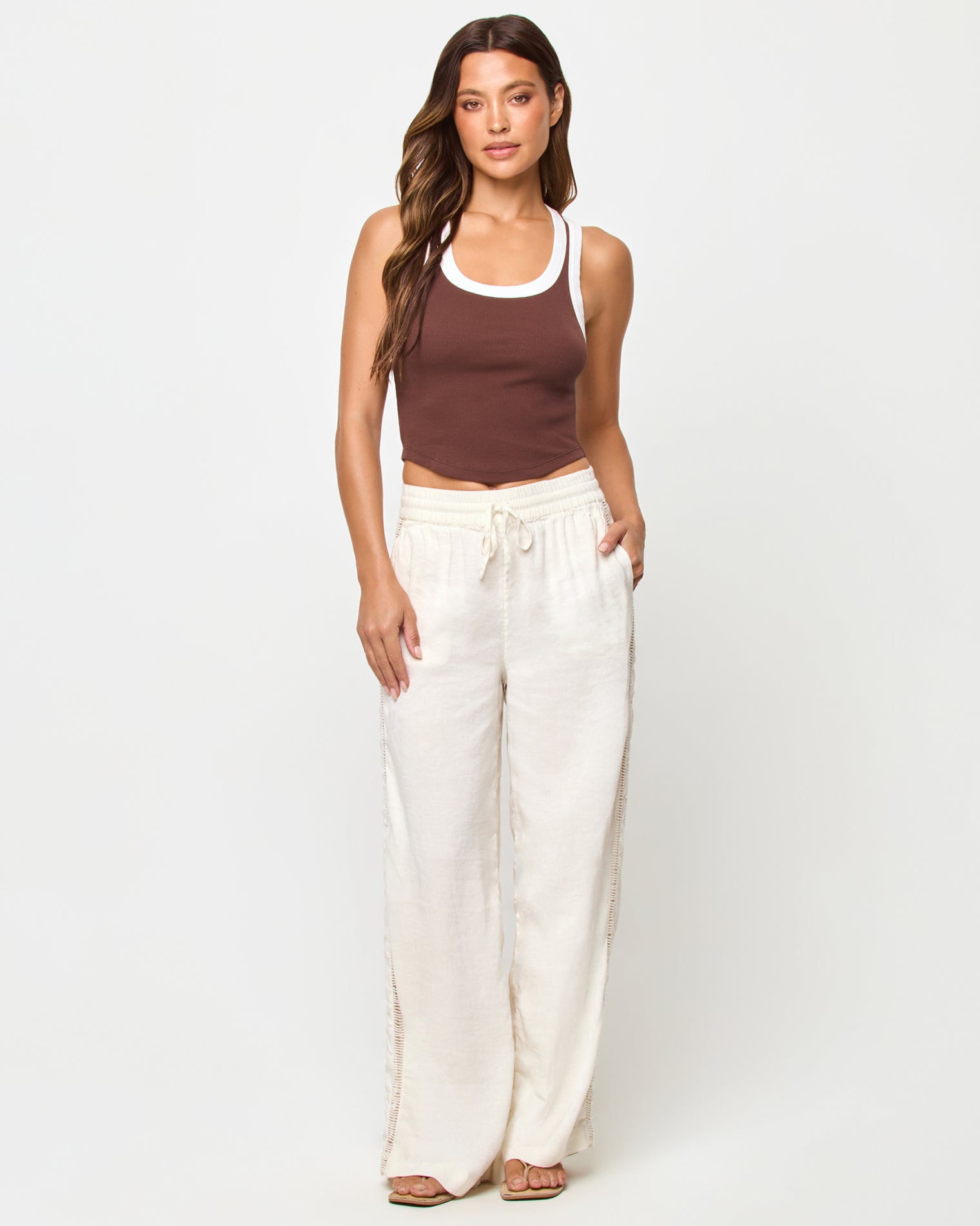 Ash Tank - Espresso Cream Full-length front view of a model wearing the LSPACE Ash Tank in espresso-cream, a cropped ribbed racerback tank with espresso brown body and cream contrast trim, styled with cream wide-leg drawstring pants and sandals.