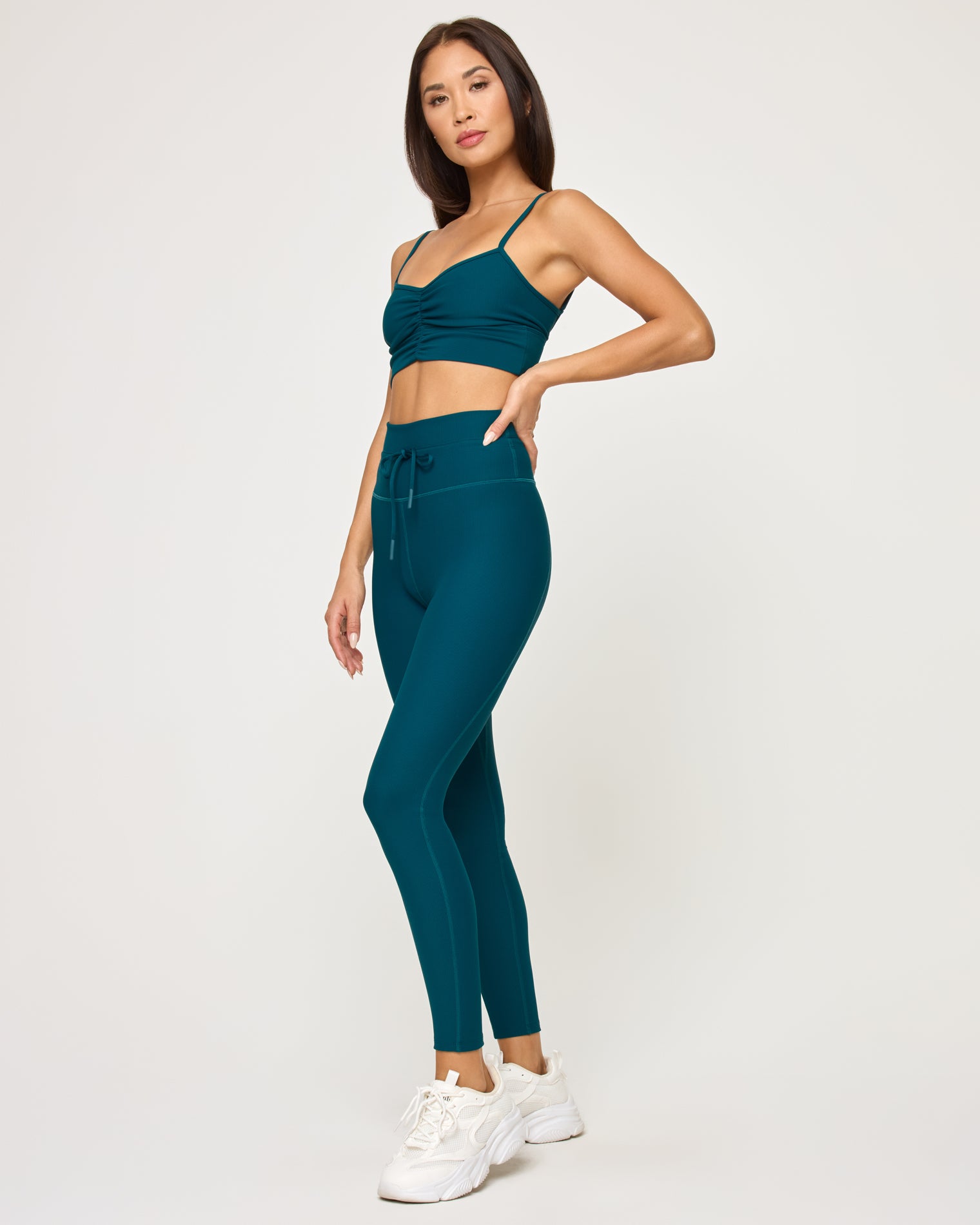 Soren Top - Deep Teal Side view of model wearing the Soren Top in deep teal with matching deep teal Turner Legging and white sneakers.