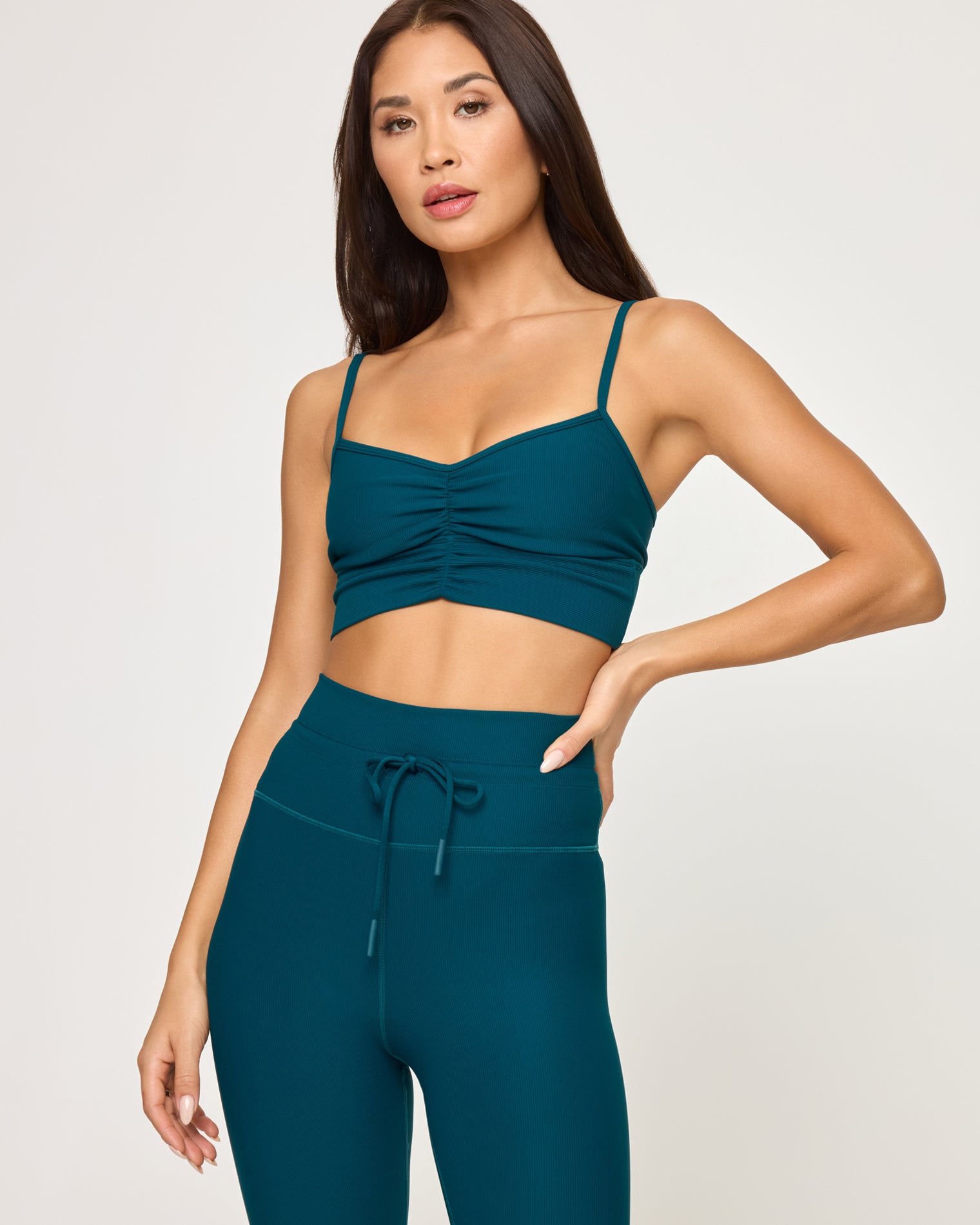 Soren Top - Deep Teal Close-up front view of model wearing the Soren Top in deep teal, a ruched sweetheart crop top with spaghetti straps, with matching deep teal Turner Legging with drawstring waist, hand on hip.
