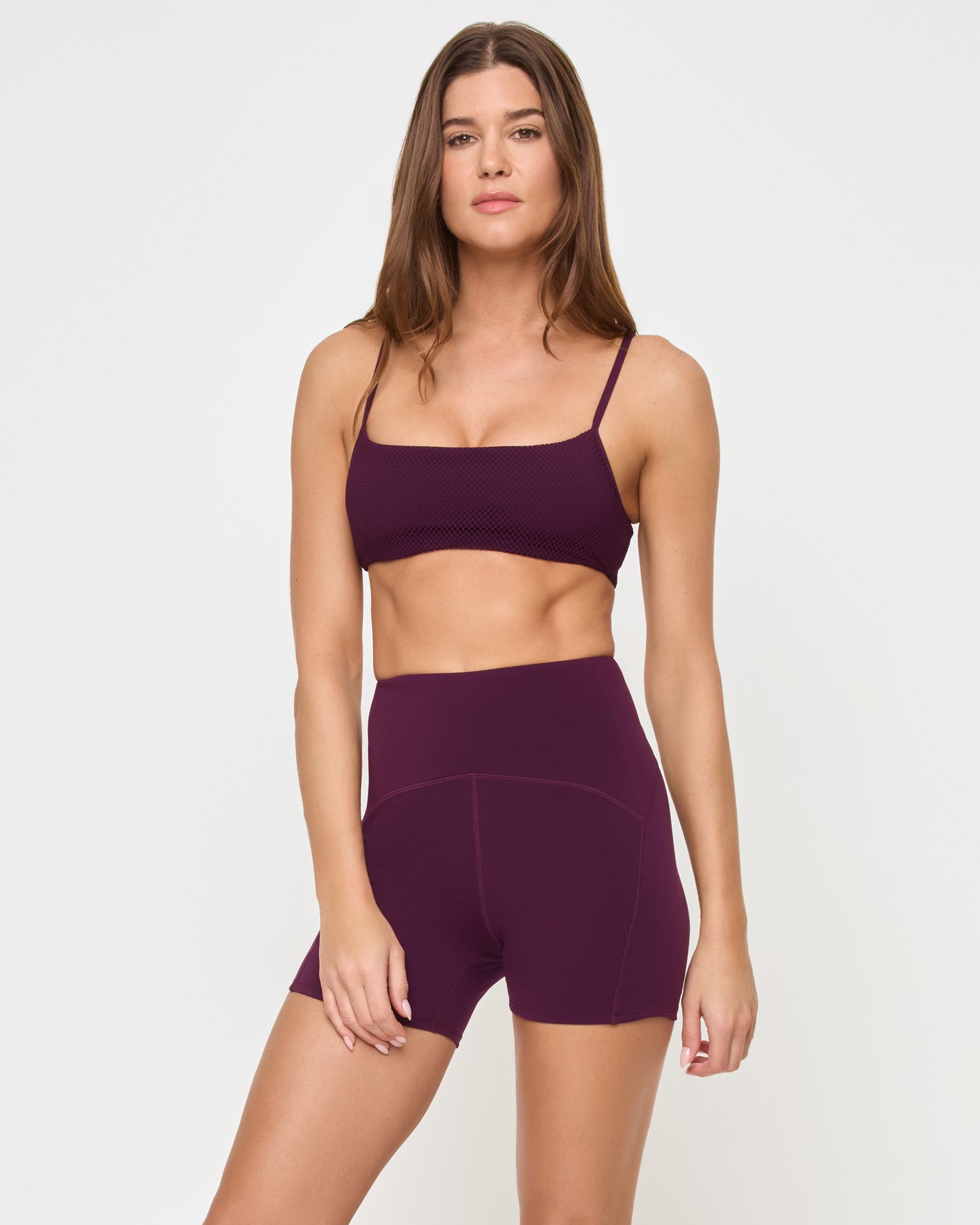 En Pointe Short - Plum Angled view of the LSPACE En Pointe Short in plum on a model against a white background, showing the profile of the high-waist active shorts, paired with the matching plum Stride Bra.
