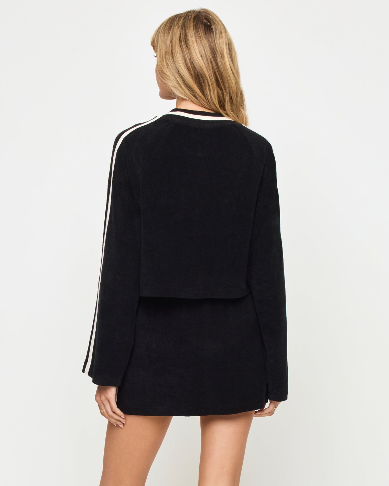 Tempo Pullover - Black-Cream Back view of the LSPACE Tempo Pullover in black-cream on a model against a light background, showing the back of the cropped crew-neck sweatshirt with cream stripe detail, paired with the matching black-cream mini active skort.