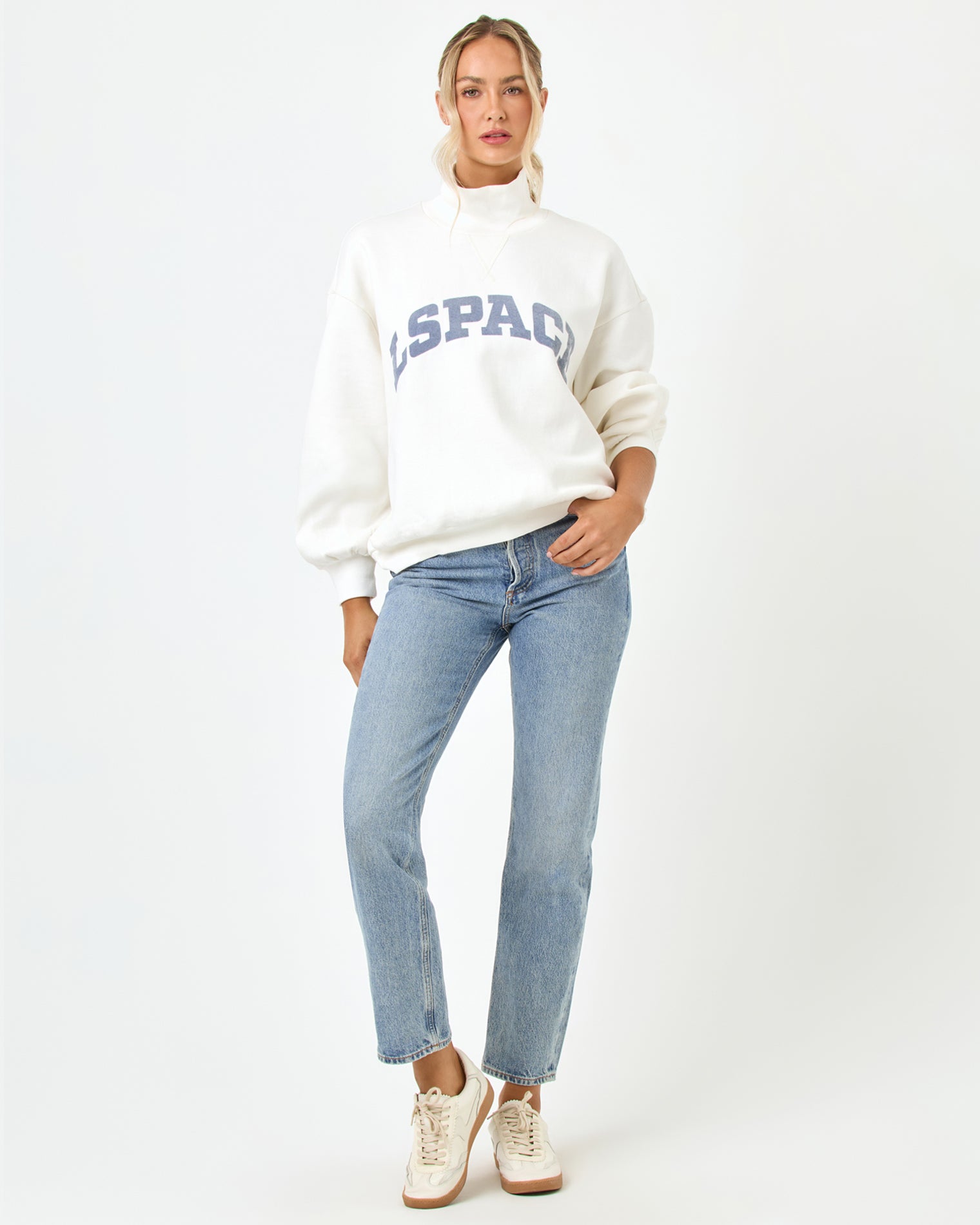 Crush Sweatshirt - Cream Front full-length studio view of the Crush Sweatshirt in cream, a cream quarter-zip pullover sweatshirt with "LSPACE" collegiate arch lettering in blue and slate, styled with light blue jeans and white sneakers.
