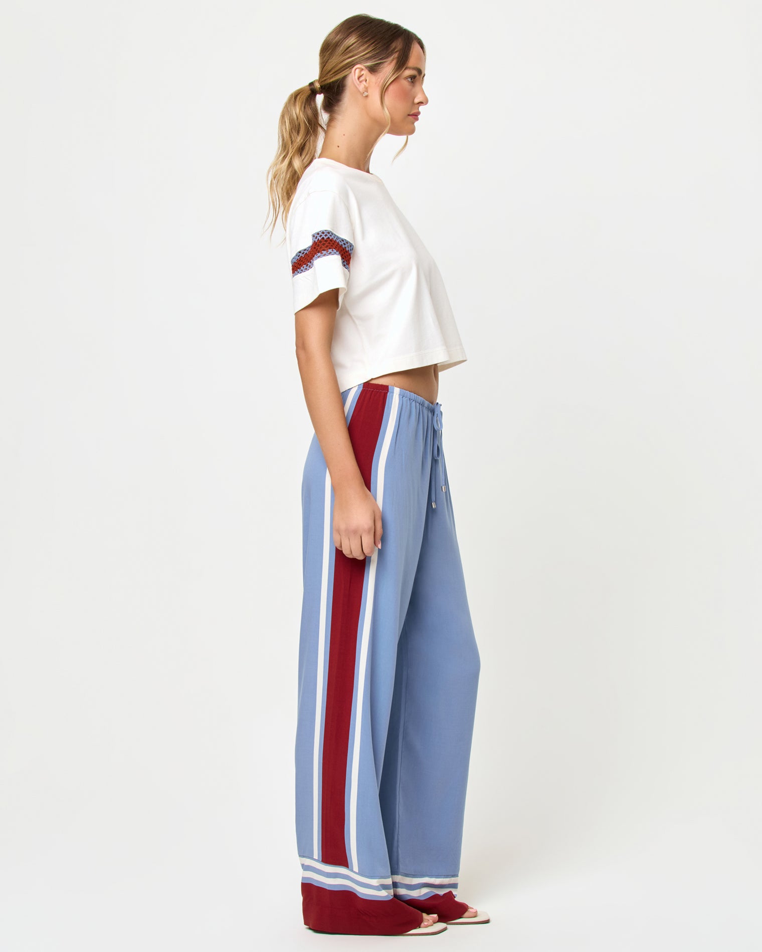 Unwind Pant - Unwind Stripe Side view of model wearing the LSPACE Unwind Pant in unwind stripe, a wide-leg pant with vertical stripe pattern.