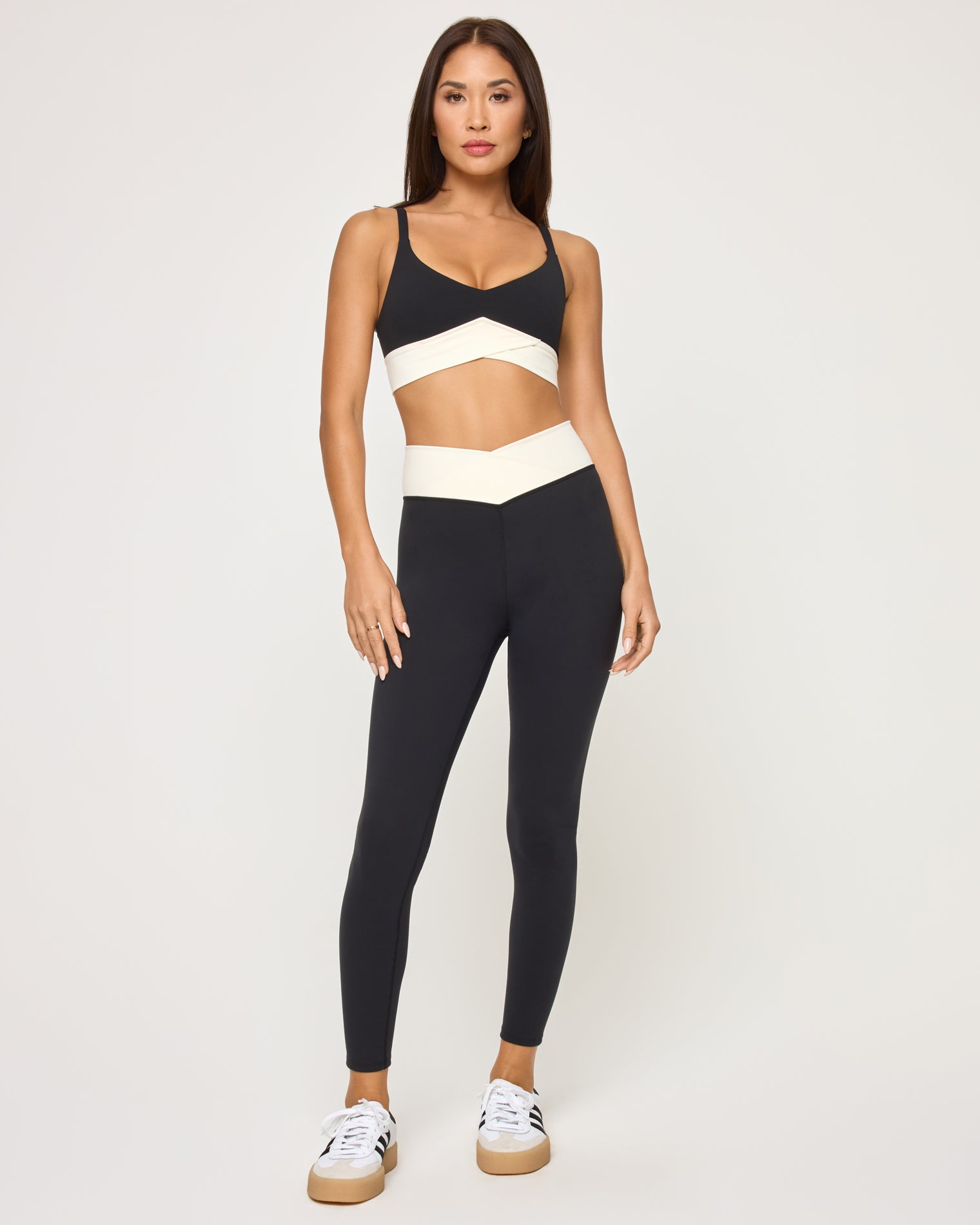 Unmatched Bra - Black-Cream Front view of model wearing the Unmatched Bra in black-cream with matching black Unmatched Legging and Adidas Samba-style sneakers.