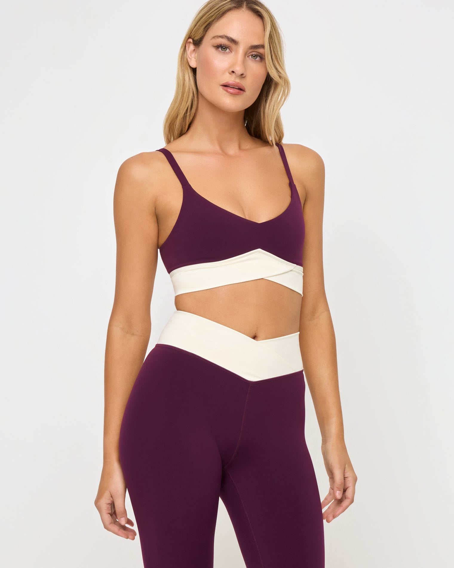 Unmatched Legging - Plum-Cream Close-up front view from the waist up of the LSPACE Unmatched Legging in plum-cream on a model against a white background, highlighting the cream crossover band and waistband detail of the matching plum bra and plum-cream legging set.