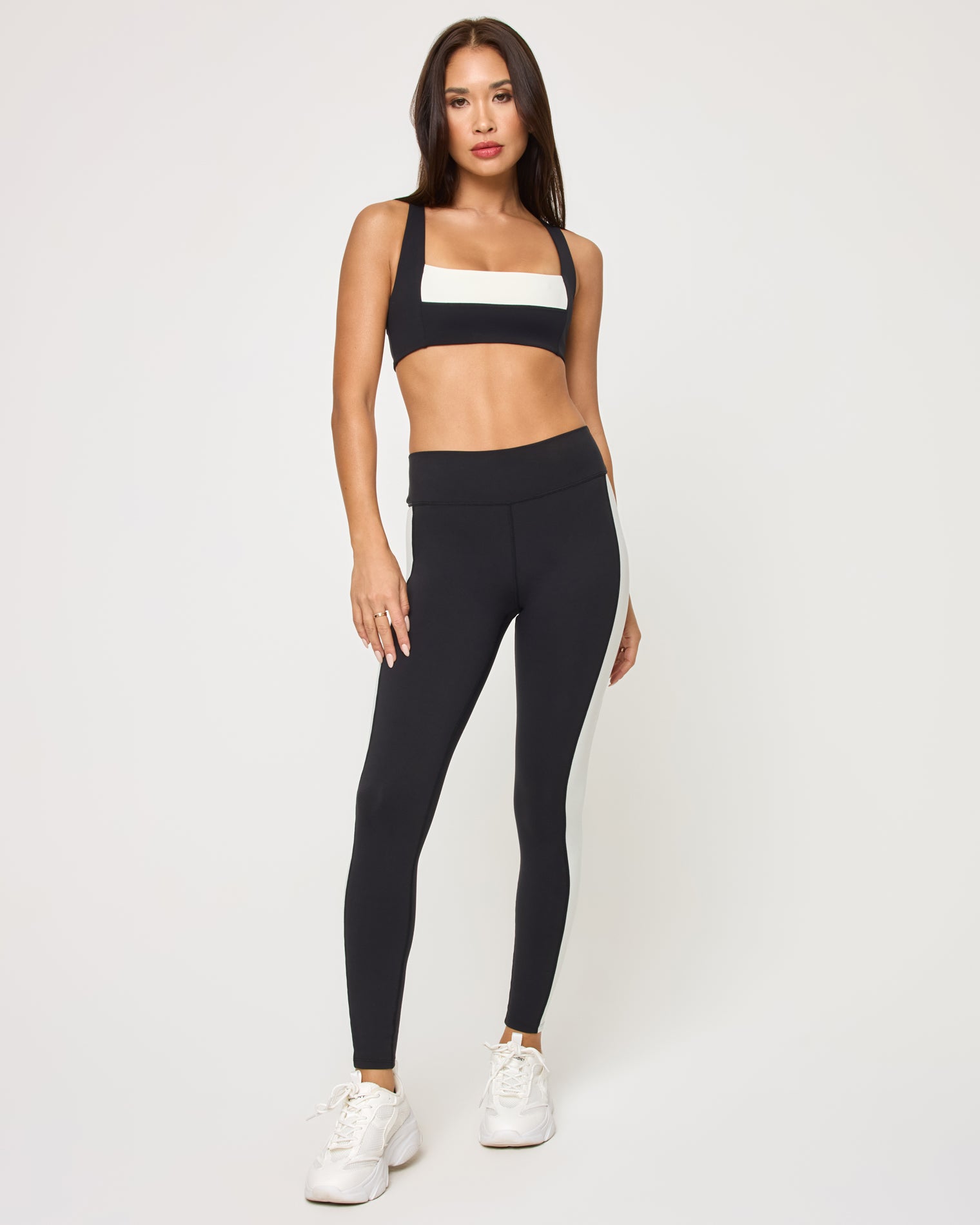 Uppercut Bra - Black-Cream Front view of the LSPACE Uppercut Bra in black-cream on a model against a white background, paired with black-cream high-rise active pants, showing the full-length outfit.