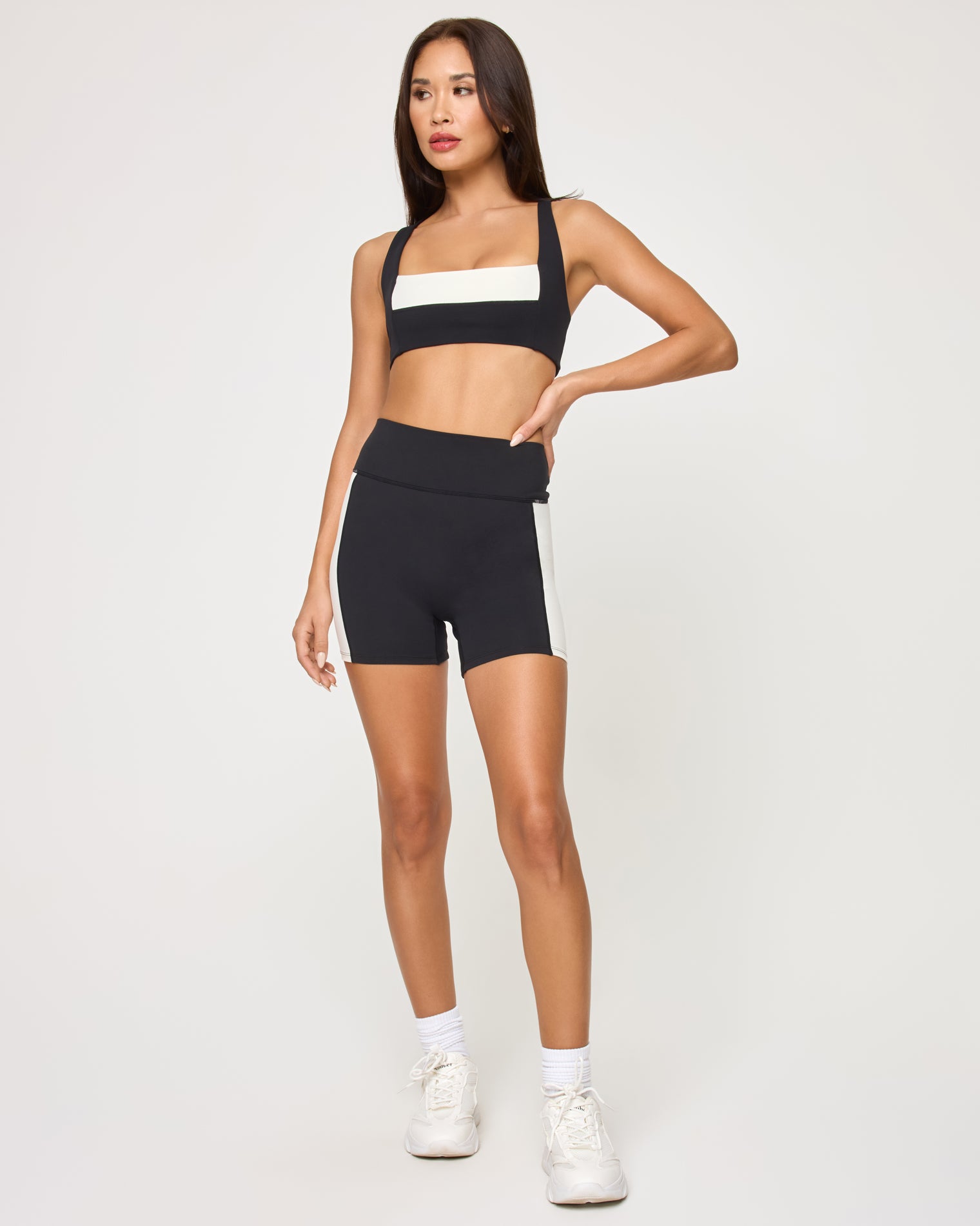 Uppercut Bra - Black-Cream Front view of the LSPACE Uppercut Bra in black-cream on a model against a white background, showing the square-neck sports bra with cream trim, paired with matching black-cream high-rise active shorts.