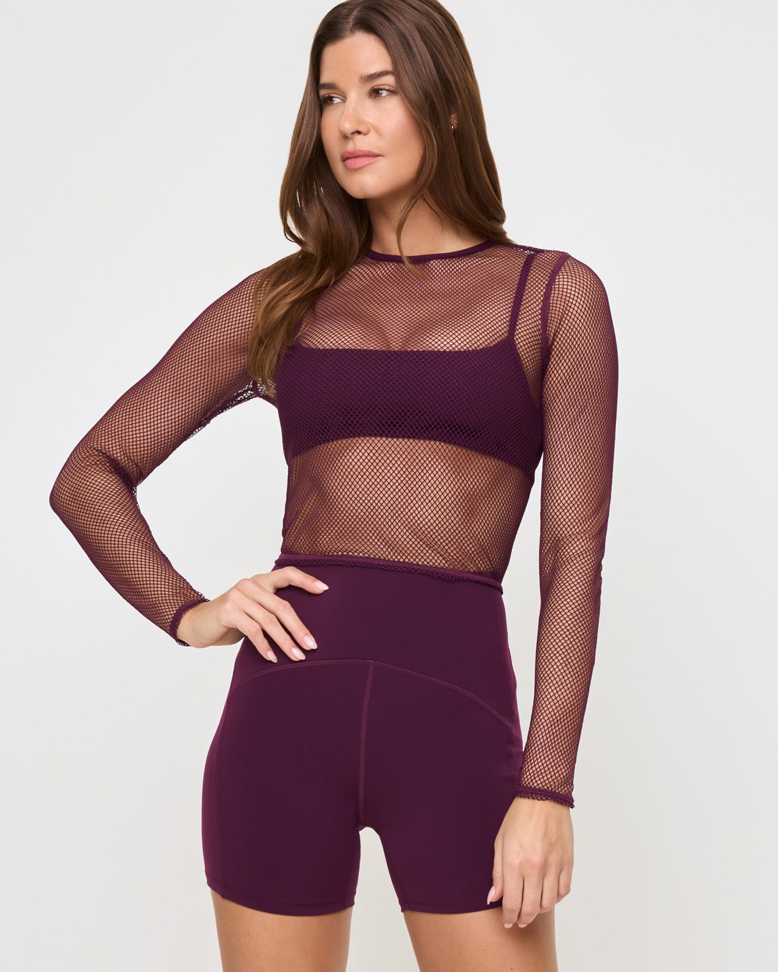 Stride Bra - Plum Close-up front view of the LSPACE Stride Bra in plum under a mesh shirt on a model against a white background, paired with plum active shorts, showing an alternate styling option.