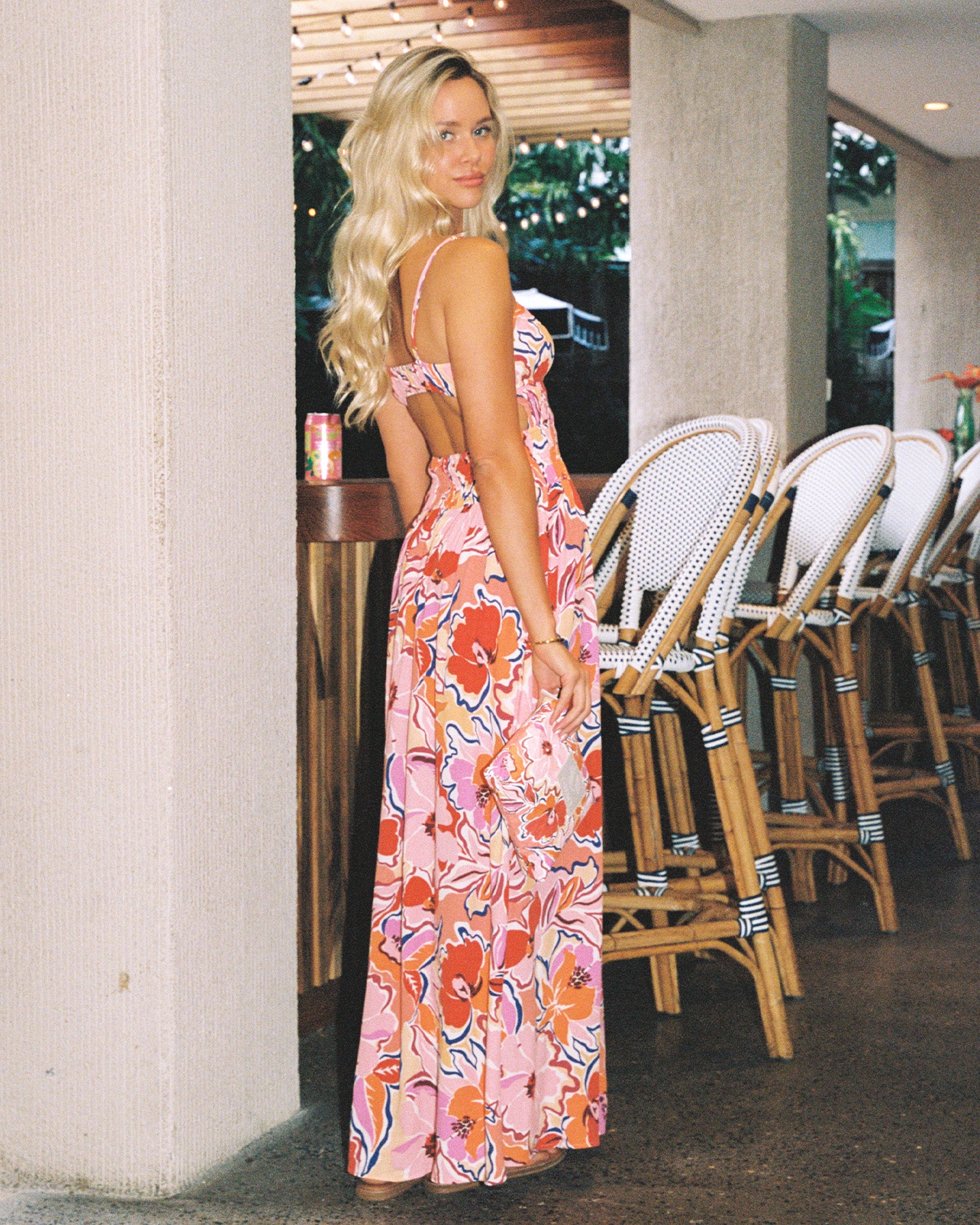 Tala Dress - Lost In The Blooms Campaign back view of a model wearing the LSPACE Tala Dress in lost in the blooms, showing the open-back cutout of the vibrant floral maxi dress, photographed in an indoor bar setting.
