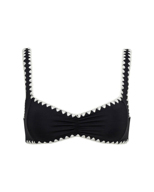 Off-model flat lay view of the LSPACE Effie Bikini Top in Black-Cream on a white background, a black bralette-style bikini top with cream zig-zag trim along the neckline, shoulder straps, and edges, featuring a center ruched detail.