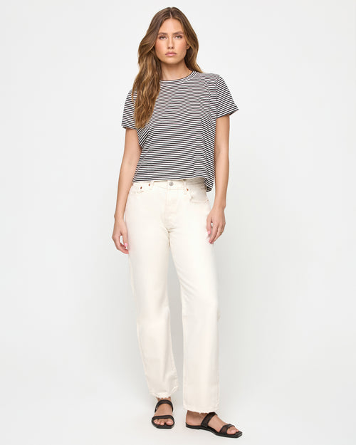 Full-length front view of a model wearing the LSPACE All Day Top in black-cream, a relaxed cropped boxy striped t-shirt with a crew neckline and short sleeves, styled with wide-leg jeans.