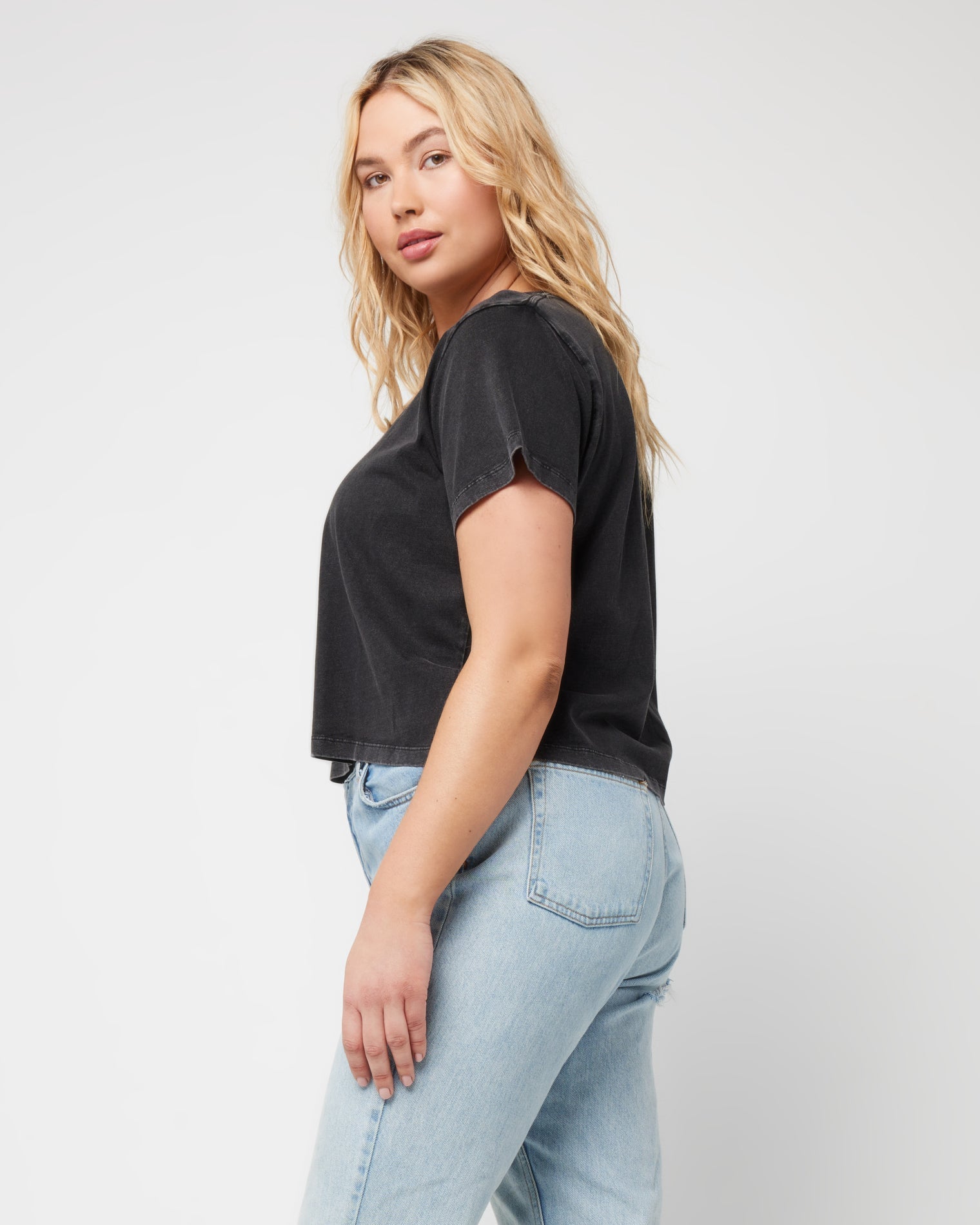 All Day Top - Black Side view of a model wearing the LSPACE All Day Top in black, styled with light wash jeans.