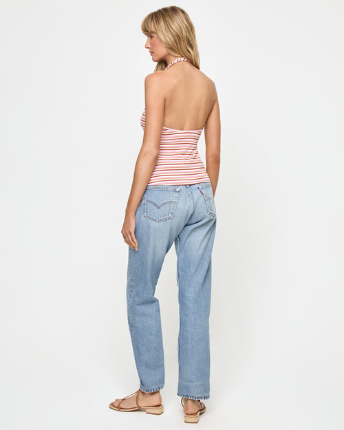 Back view of a model wearing the LSPACE Callie Halter in azalea stripe, showing the open back design and neck-tie closure, styled with light-wash jeans.