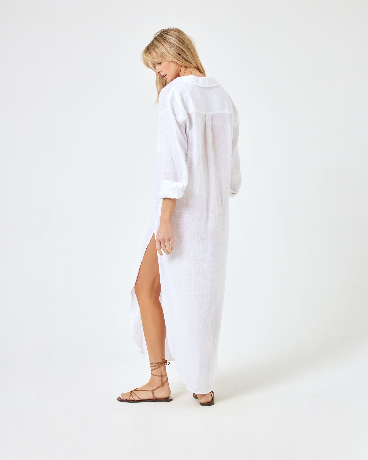 Capistrano Tunic - White Back angled view of a model wearing the LSPACE Capistrano Tunic in white linen, looking down.