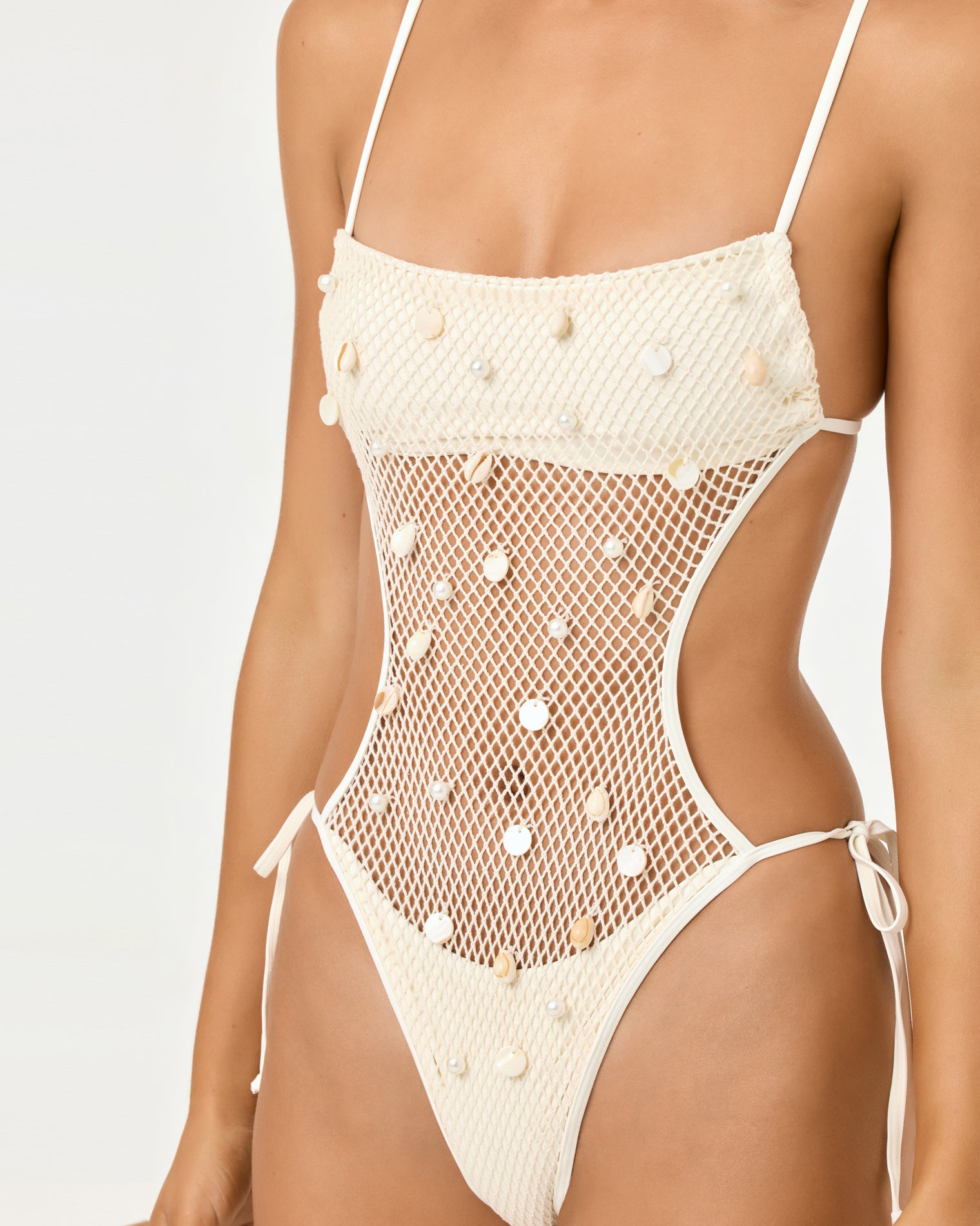 Catching Up One Piece - Cream Close-up front view of a model wearing the LSPACE cream Catching Up One Piece showing the crochet bandeau bodice with shell and pearl embellishments, sheer mesh midsection, and side tie details.
