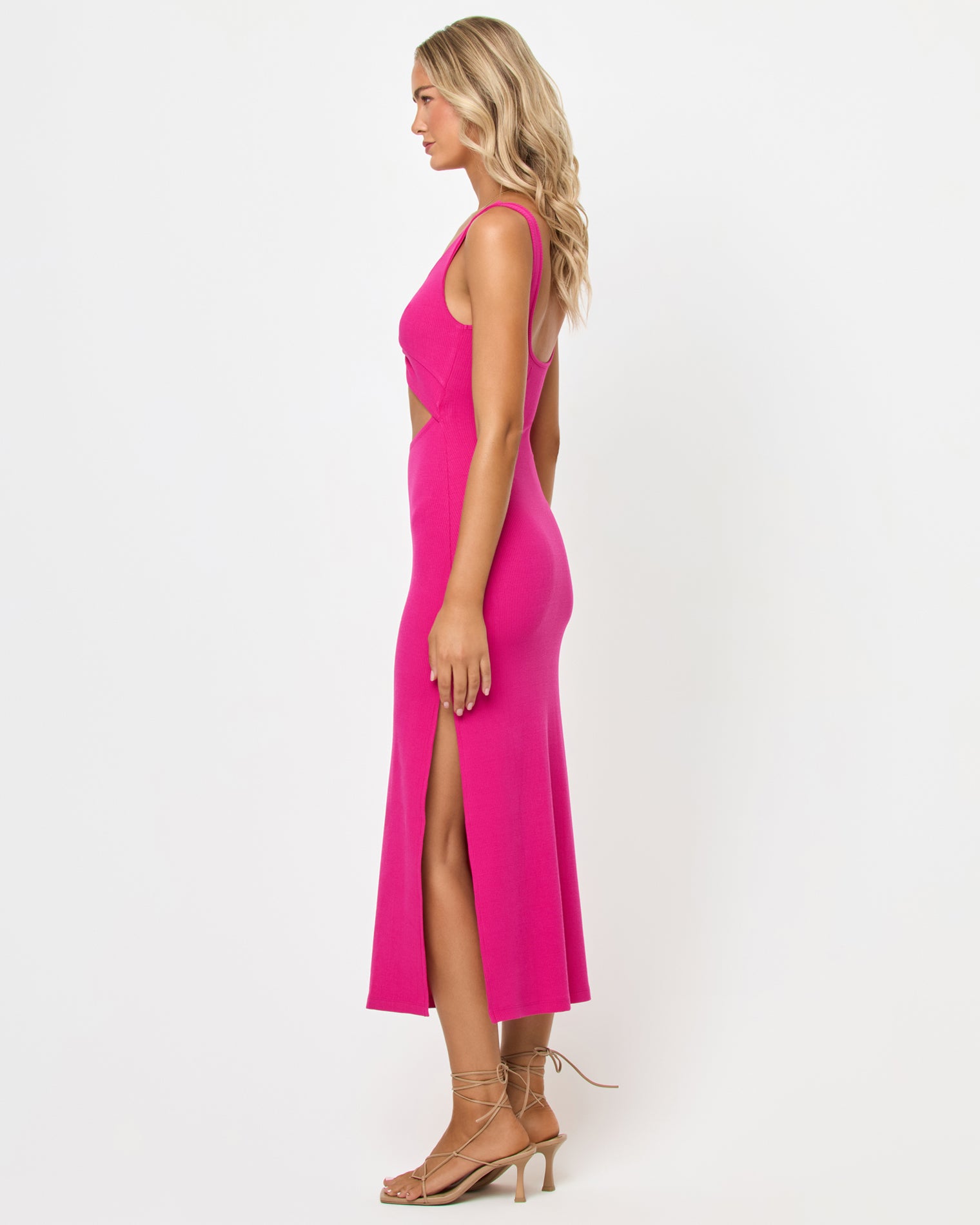 Camille Dress - Bougainvillea Side view of a model wearing the LSPACE Camille Dress in Bougainvillea, showing the fitted ribbed knit silhouette, side cutout detail, and side slit, on a neutral studio background.