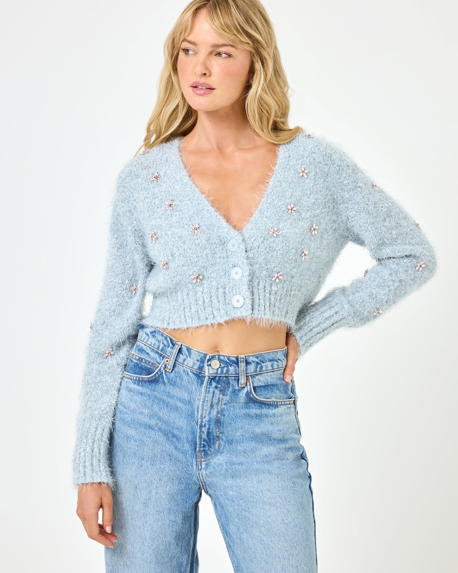 Crystal Cardigan - Dove Close-up front view of a model wearing the LSPACE Crystal Cardigan in dove, showcasing the fluffy knit fabric, crystal floral embellishments, and button-front detail of the cropped cardigan.