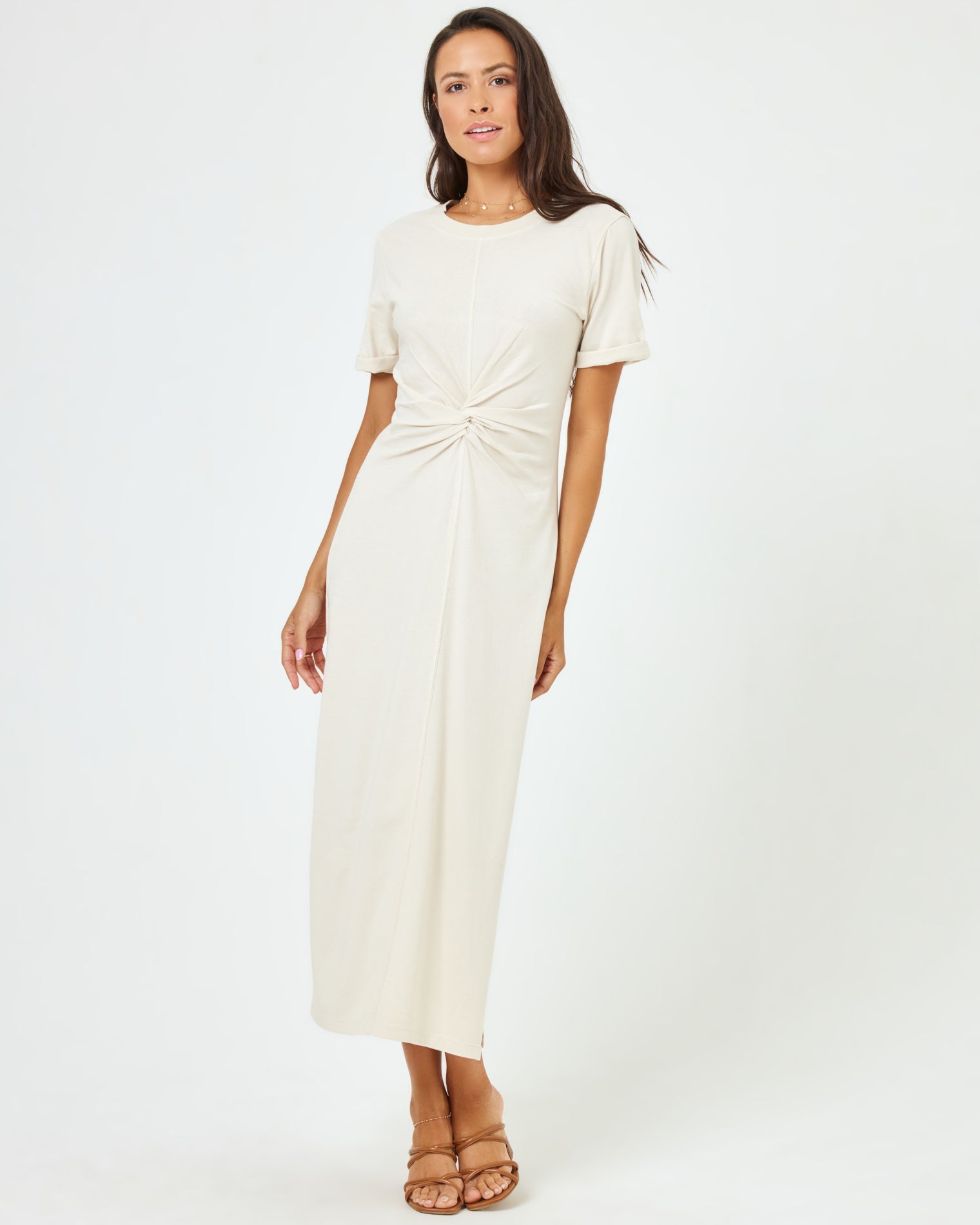 Drew Dress - Cream Front view of a model wearing the LSPACE Drew Dress in cream, a short-sleeve jersey midi dress with a ring detail at the twisted waist.
