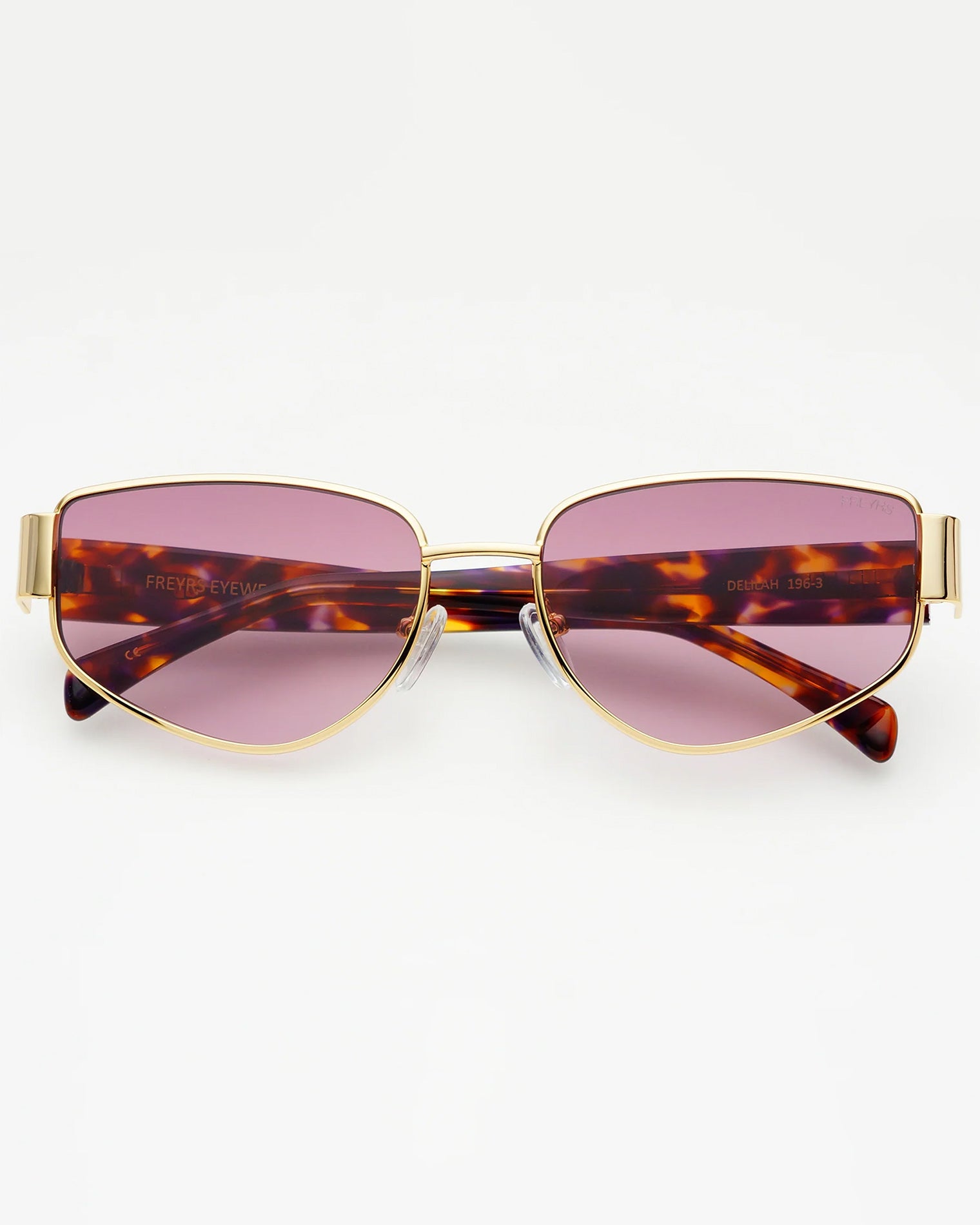 Freyrs Delilah Sunglasses - Gold Off-model image of the Freyrs Delilah Sunglasses in gold, folded flat with gold metal frame and pink-tinted lenses.
