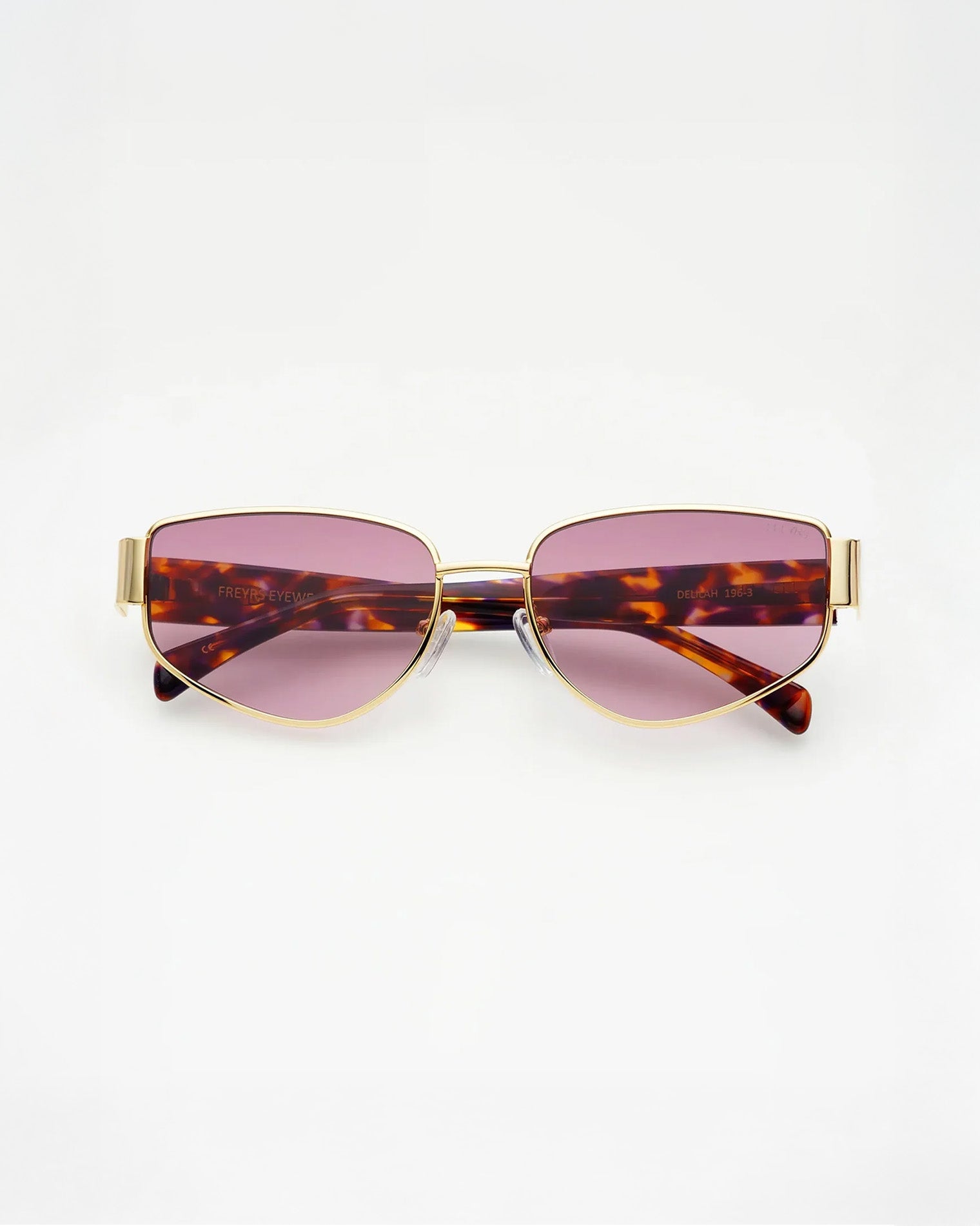 Freyrs Delilah Sunglasses - Gold Off-model image of the Freyrs Delilah Sunglasses in gold, folded flat with gold metal frame and pink-tinted lenses.