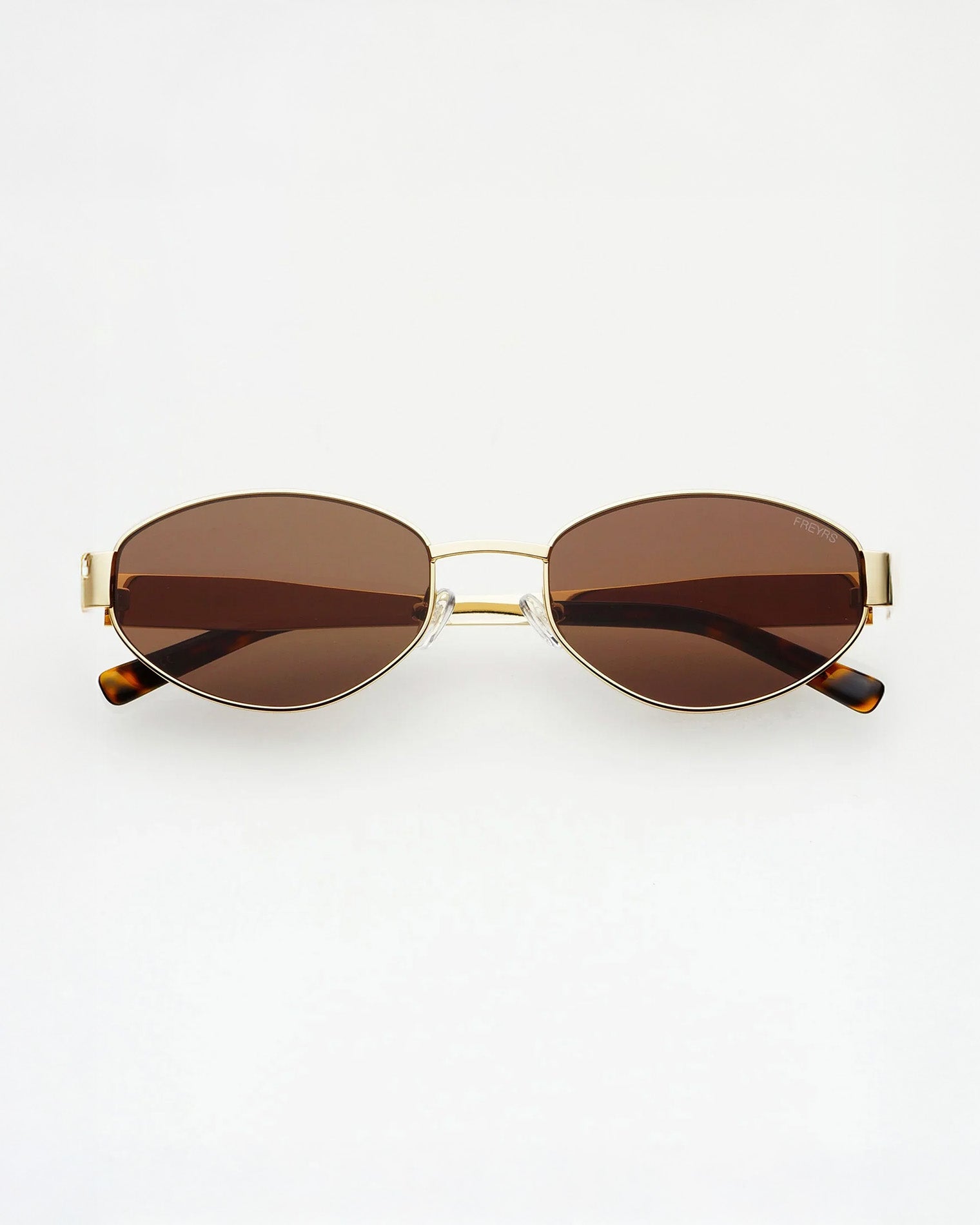 Oval sunglasses with brown tinted lenses, a thin gold metal frame, and tortoiseshell temple tips, shown against a plain white background.