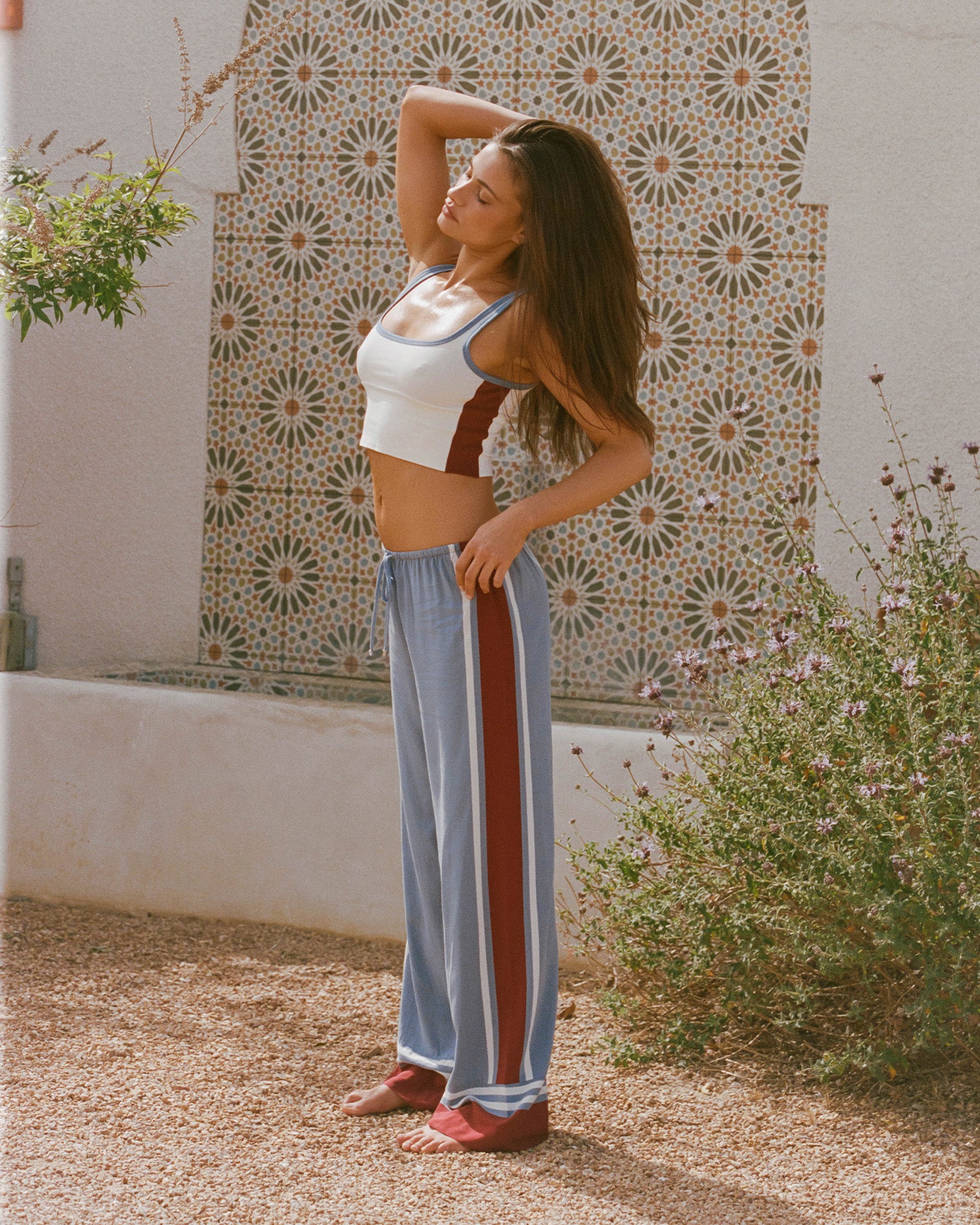 Unwind Pant - Unwind Stripe Unwind Stripe | Badge:New Arrival_#B2AC88_#ffffff'
Lifestyle image of model wearing the LSPACE Unwind Pant in unwind stripe, a relaxed-fit striped pant.