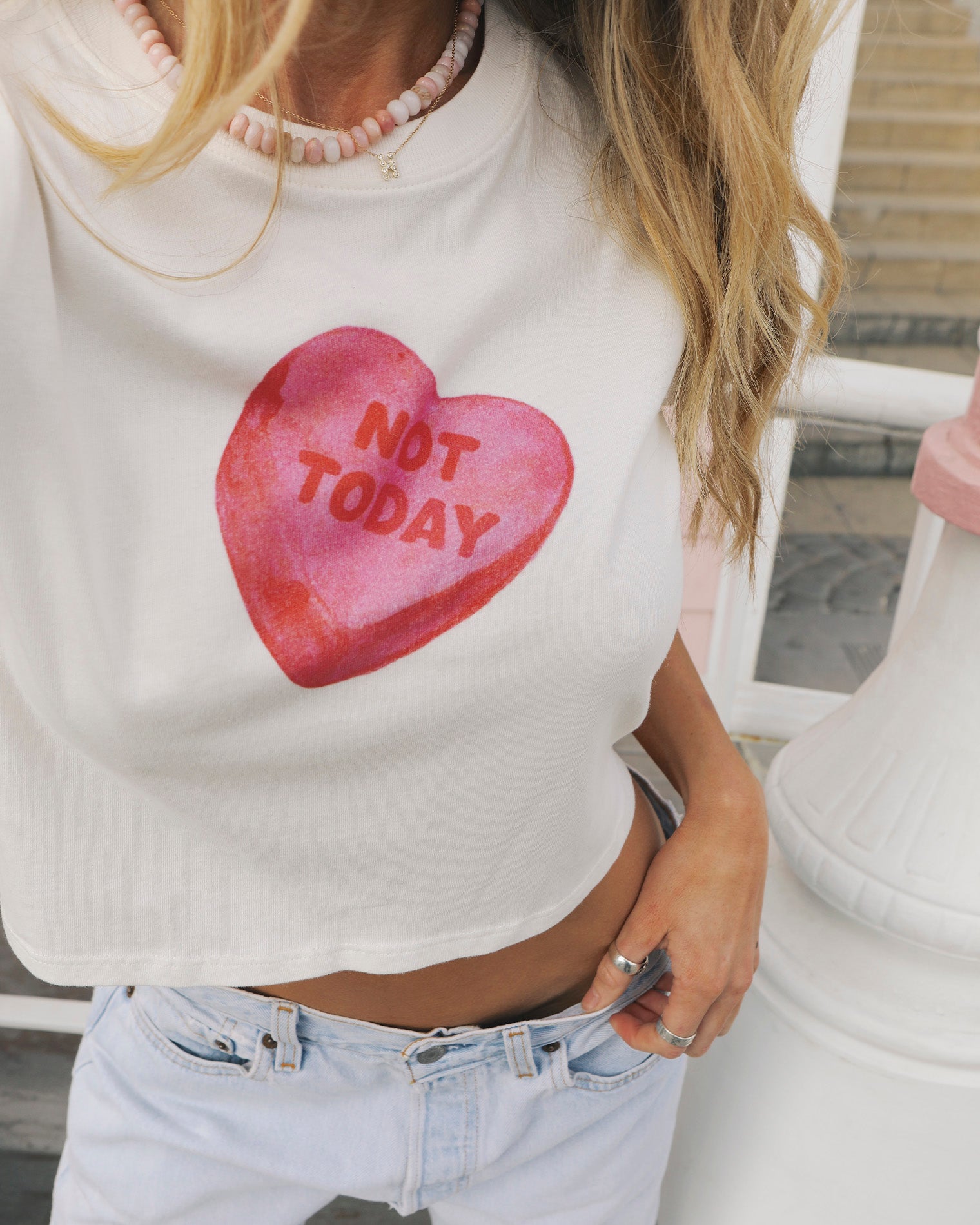 Merci Baby Tee - Not Today Close-up of the LSPACE Merci Baby Tee in Not Today, highlighting the oversized pink candy heart graphic reading "Not Today" on the white cropped front.
